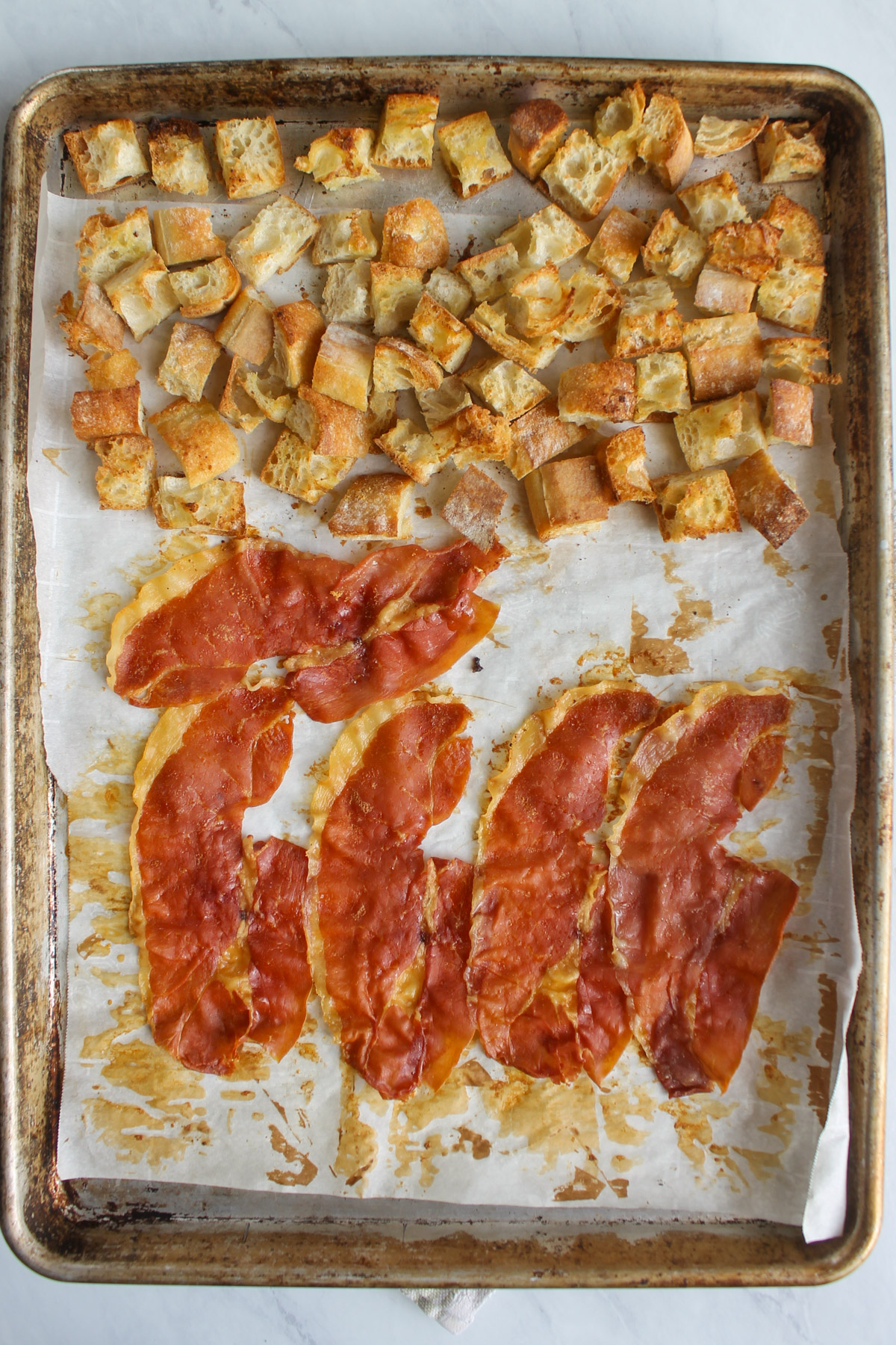 Baked croutons and crispy prosciutto on a sheet pan hot from the oven.