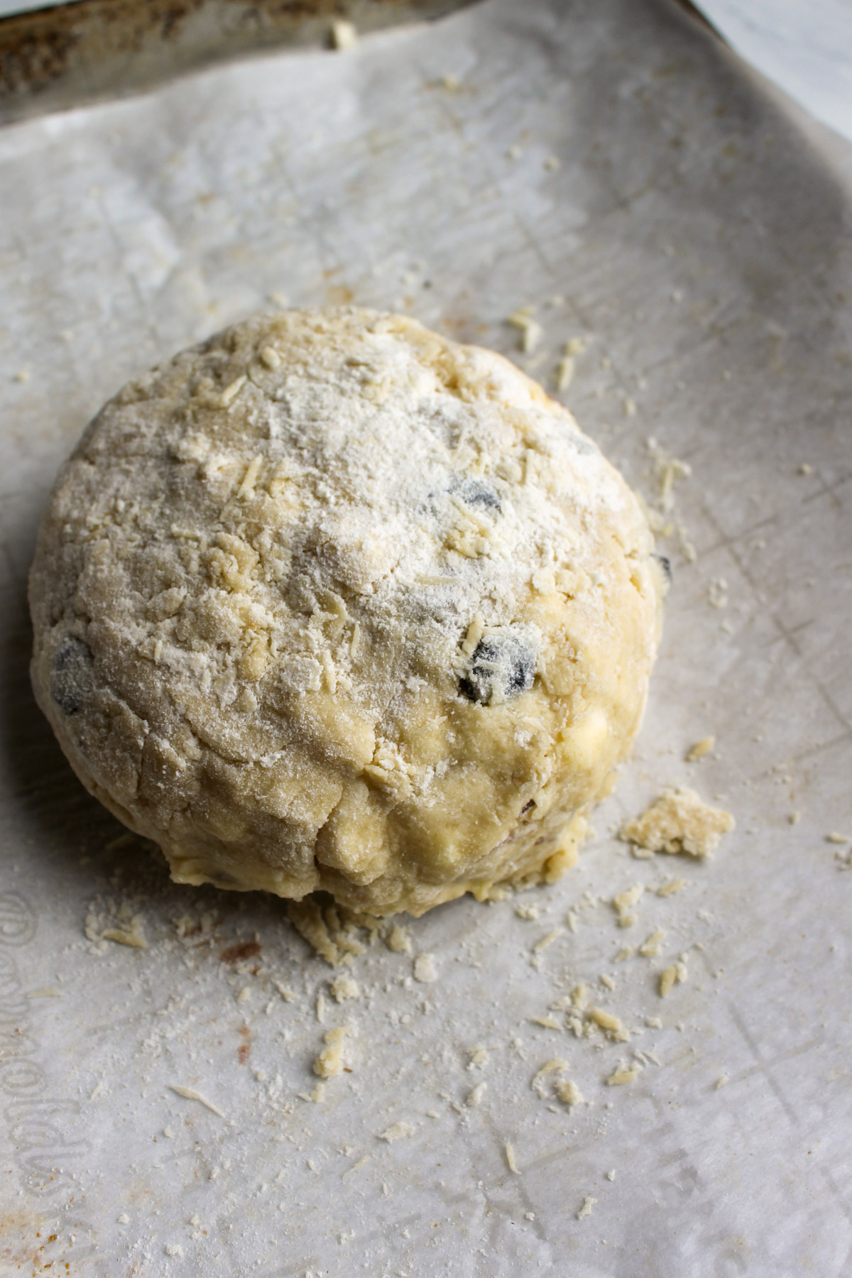 A round ball of almond cherry scone dough dusted with flour.