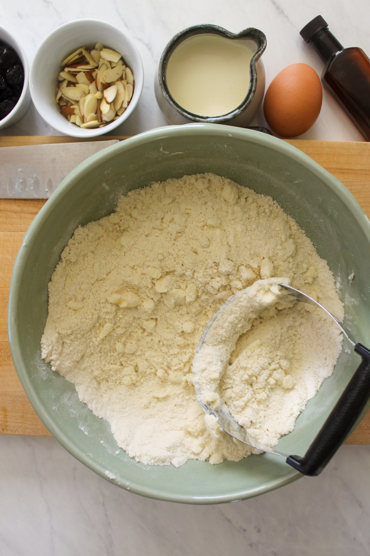 Dry ingredients in a bowl with butter being cut in with a pastry cutter.