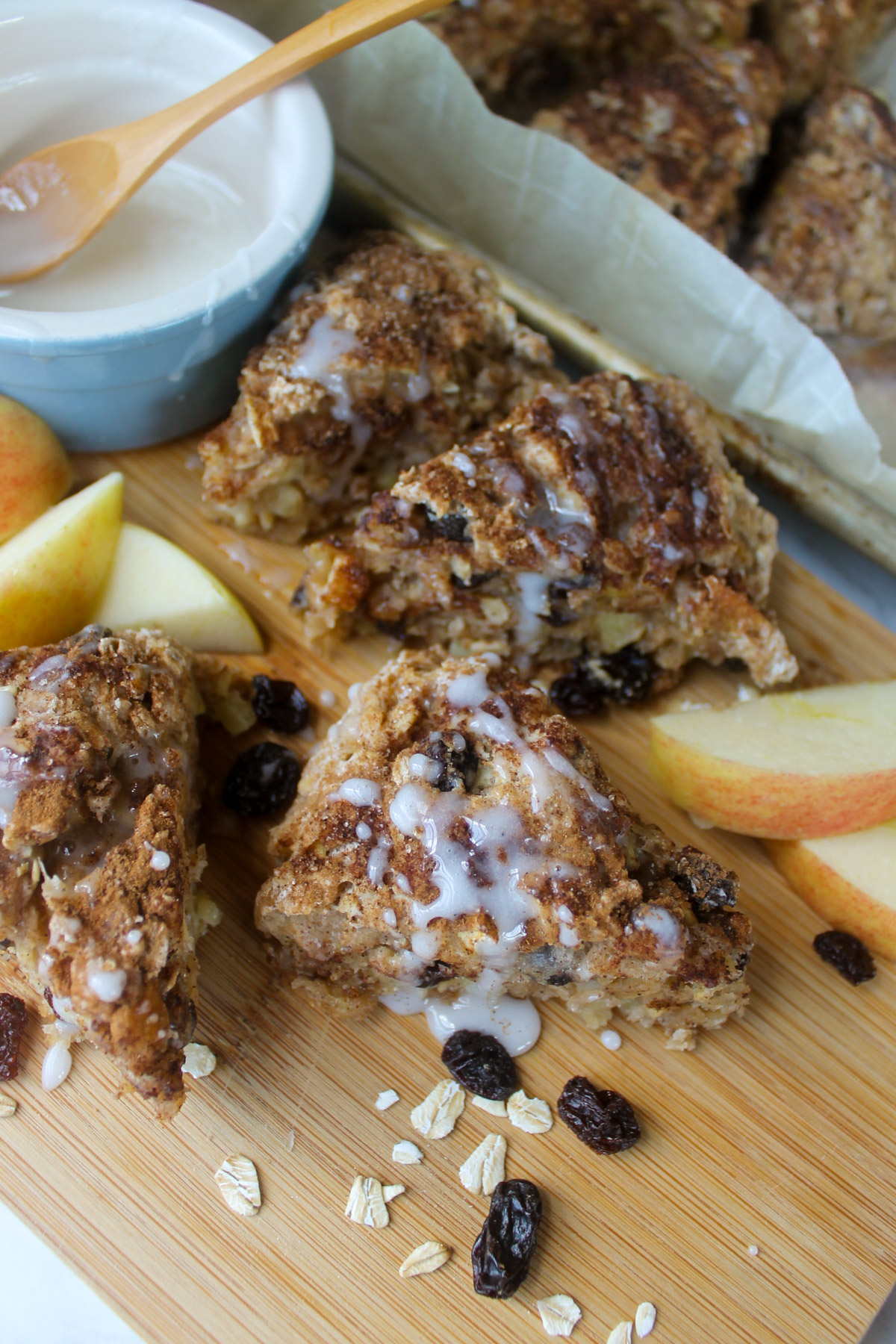 Triangle cut apple cinnamon scones on a cutting board drizzled with white icing.