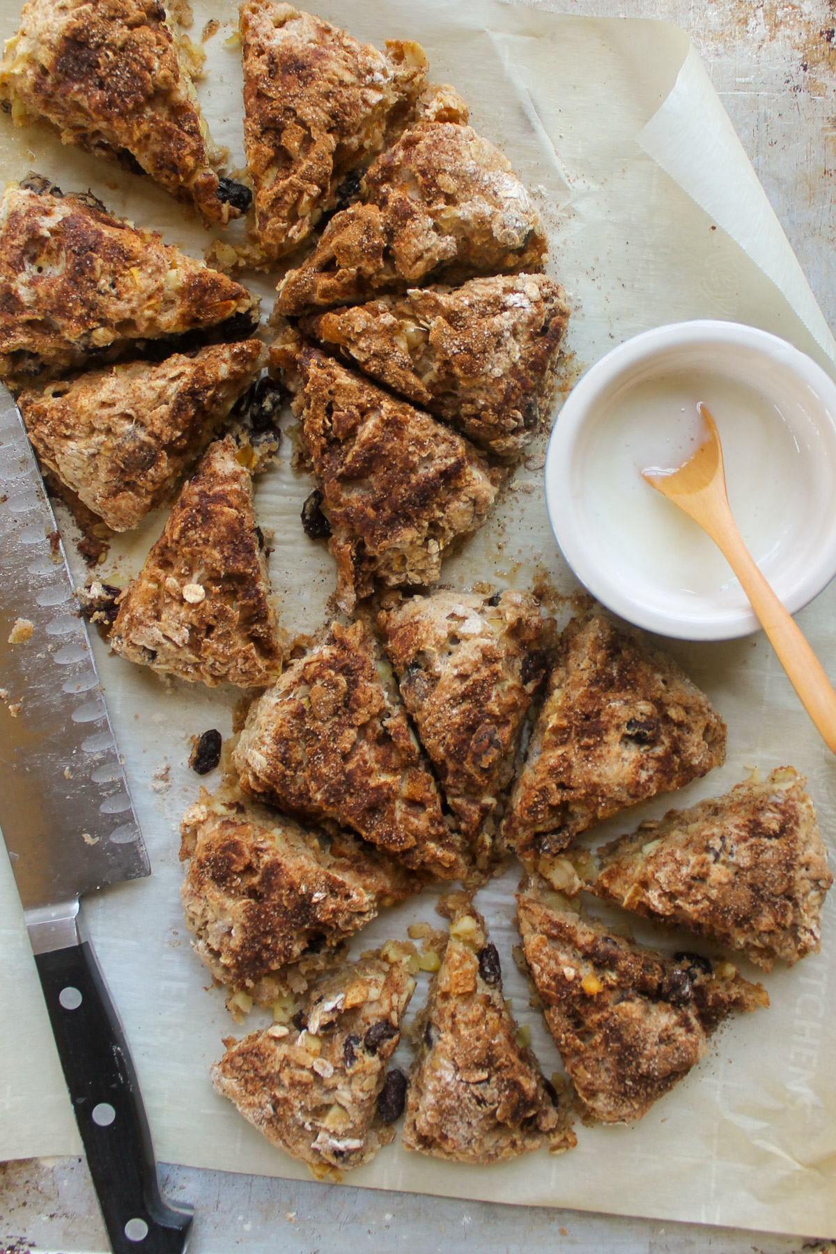 Baked scones cut into wedges on a sheet pan with a bowl of glaze to drizzle.