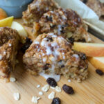 A wedge of Apple Cinnamon Raisin Scone drizzled with white glaze.