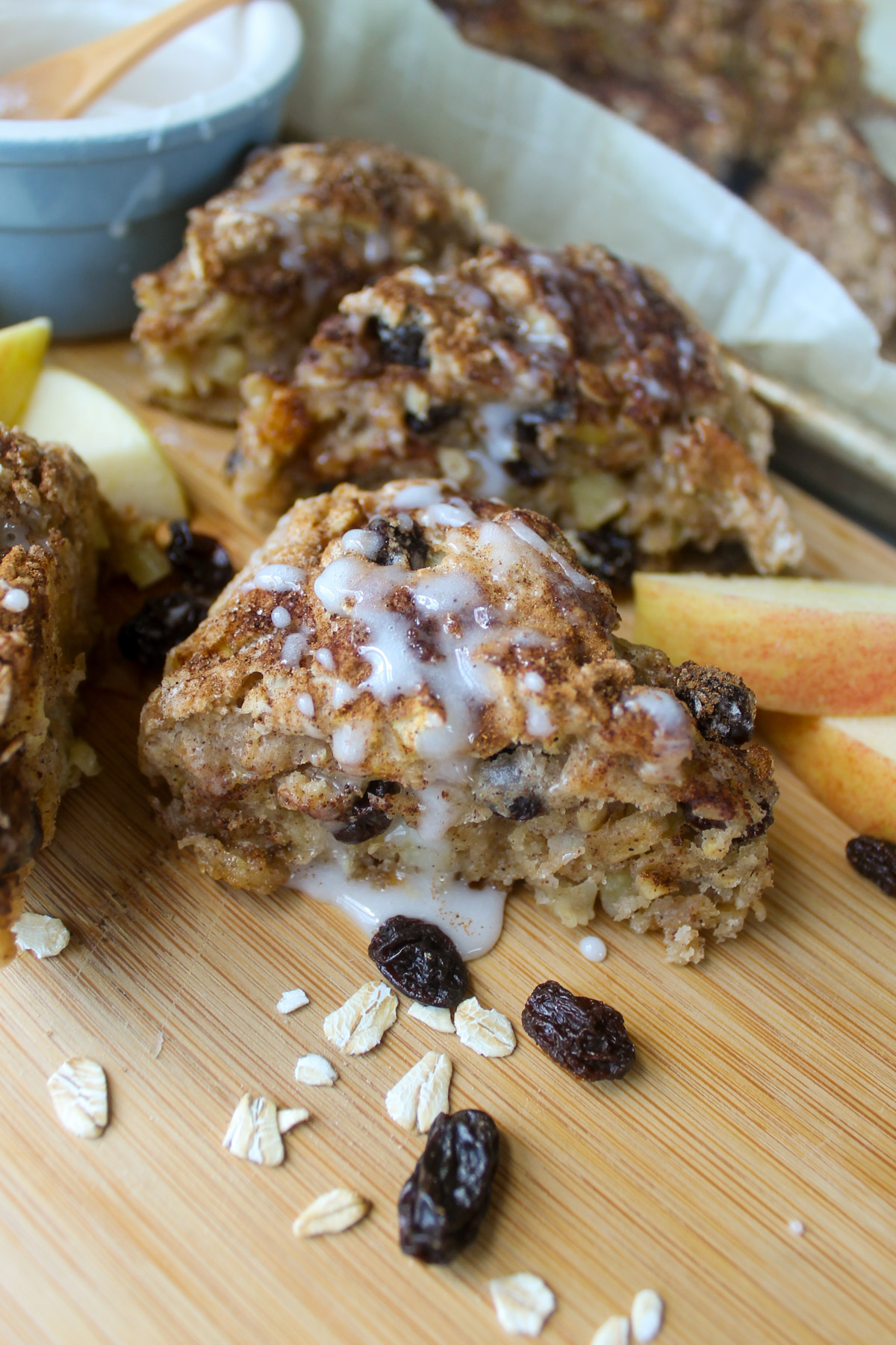 Apple Raisin Scone wedges on a cutting board with a bowl of glaze.