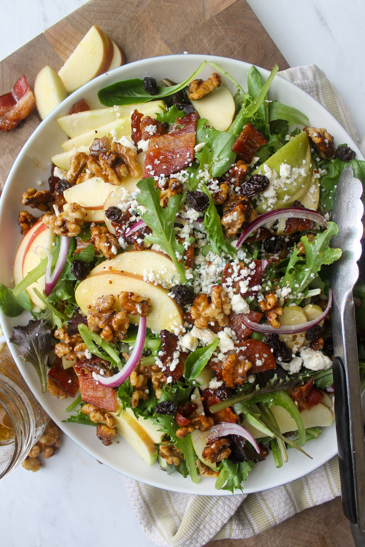 A plate of salad with apple slices, walnuts, blue cheese, raisins and red onion.