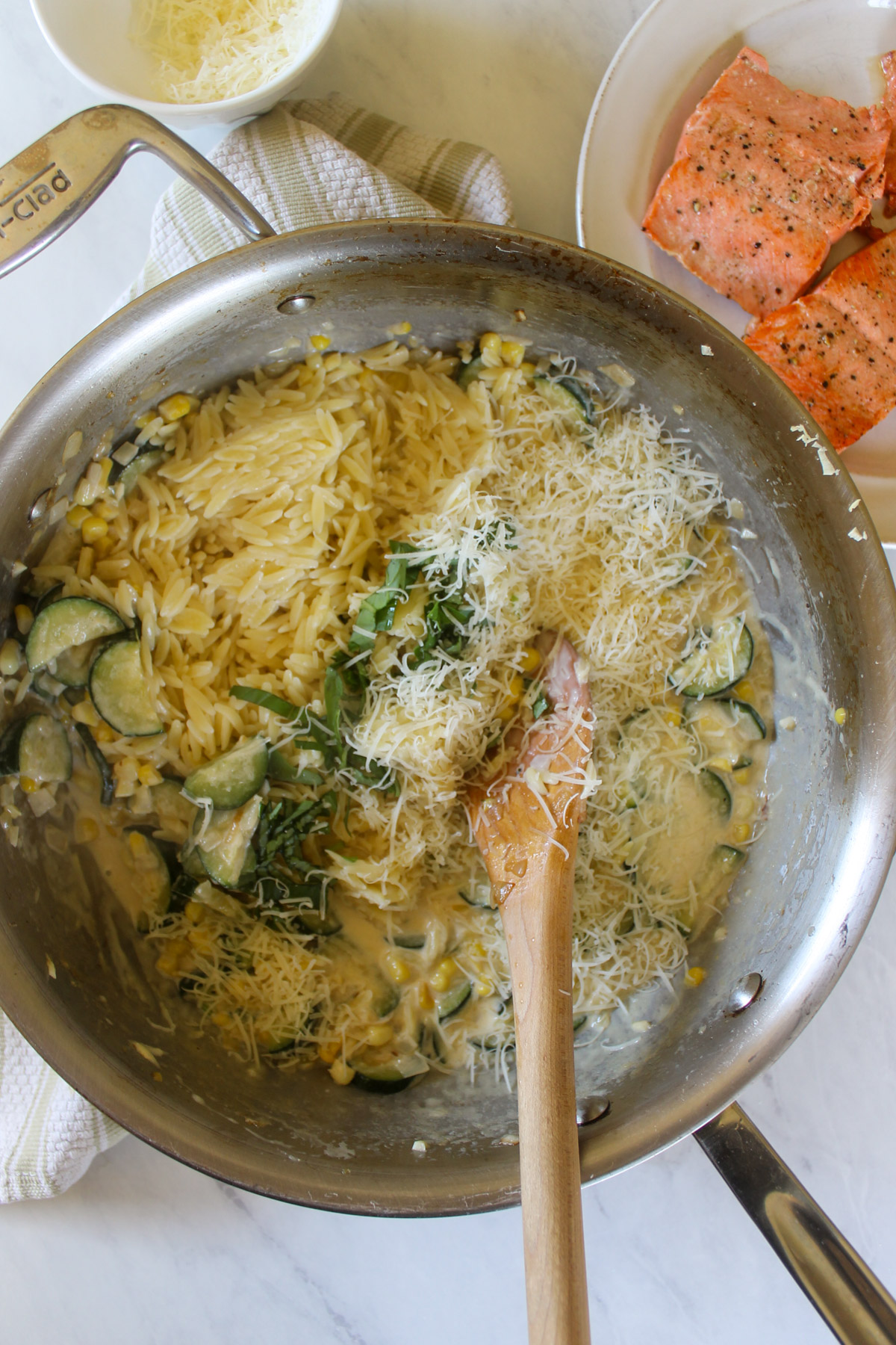 Cooked orzo pasta and basil being added to zucchini corn cream sauce.