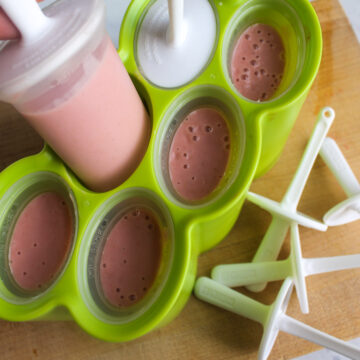 Homemade pink strawberry banana yogurt popsicle mix poured into a popsicle mold.