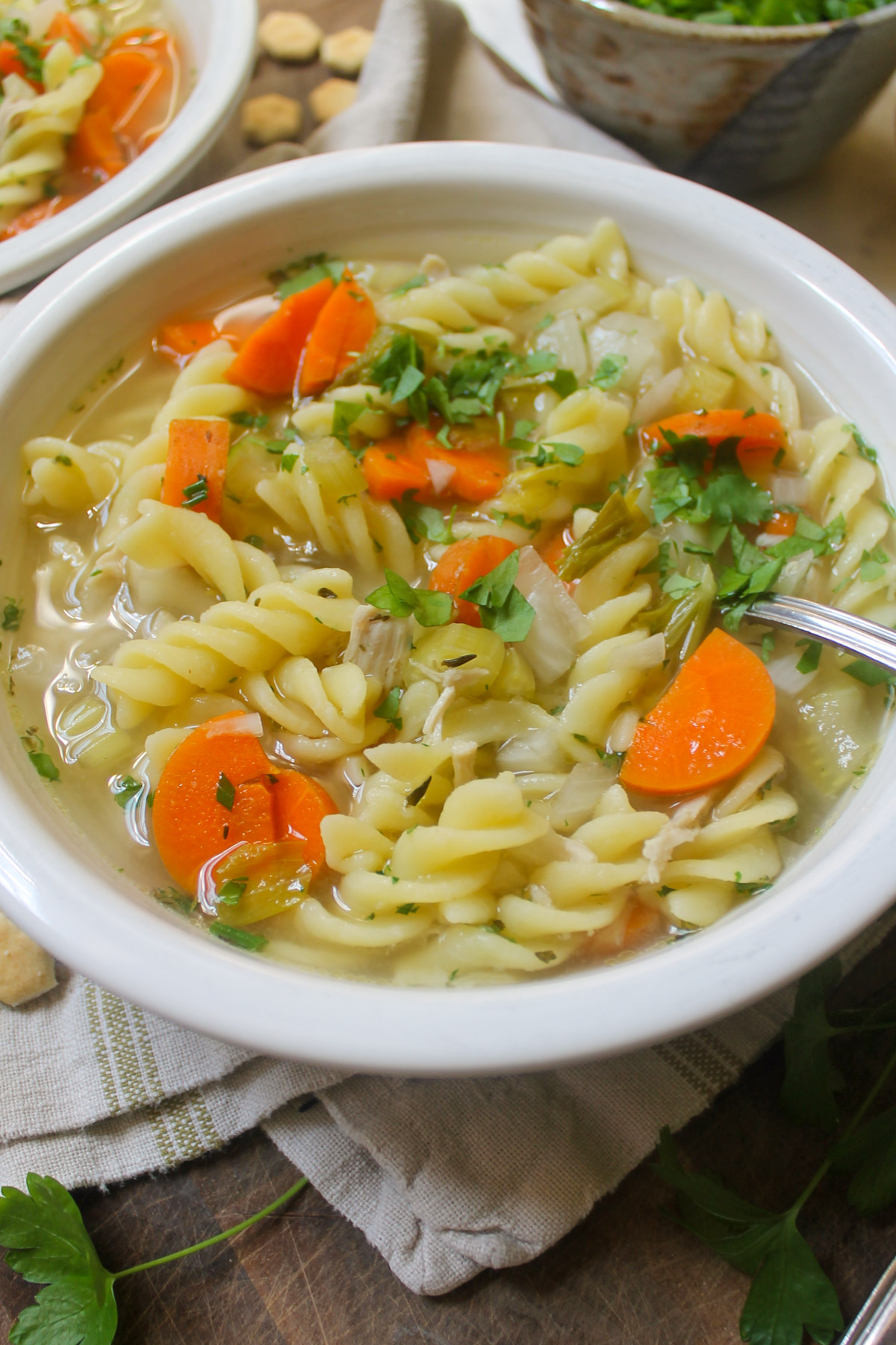 A bowl of Chicken Noodle Soup with fresh herbs.