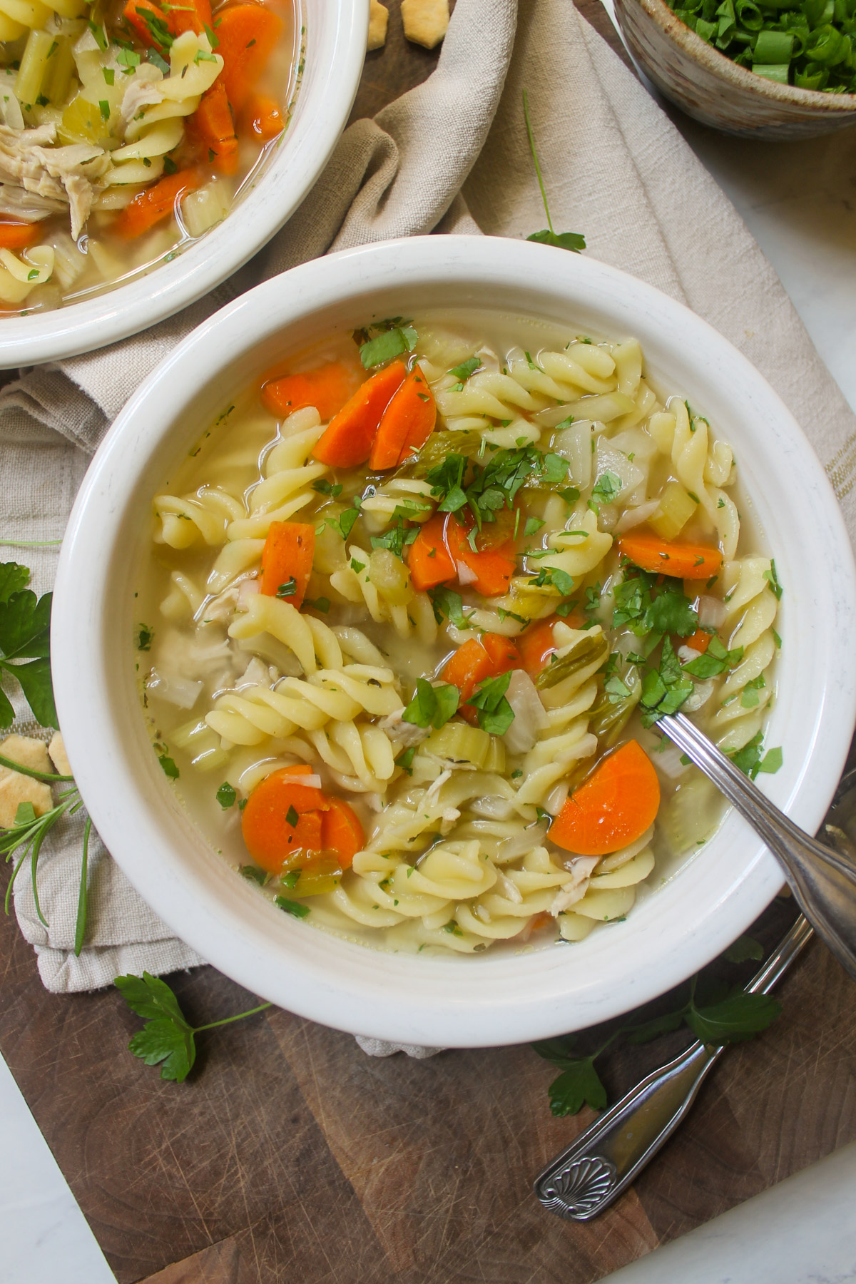 Bowls of Chicken Noodle Soup on a wooden cutting board.