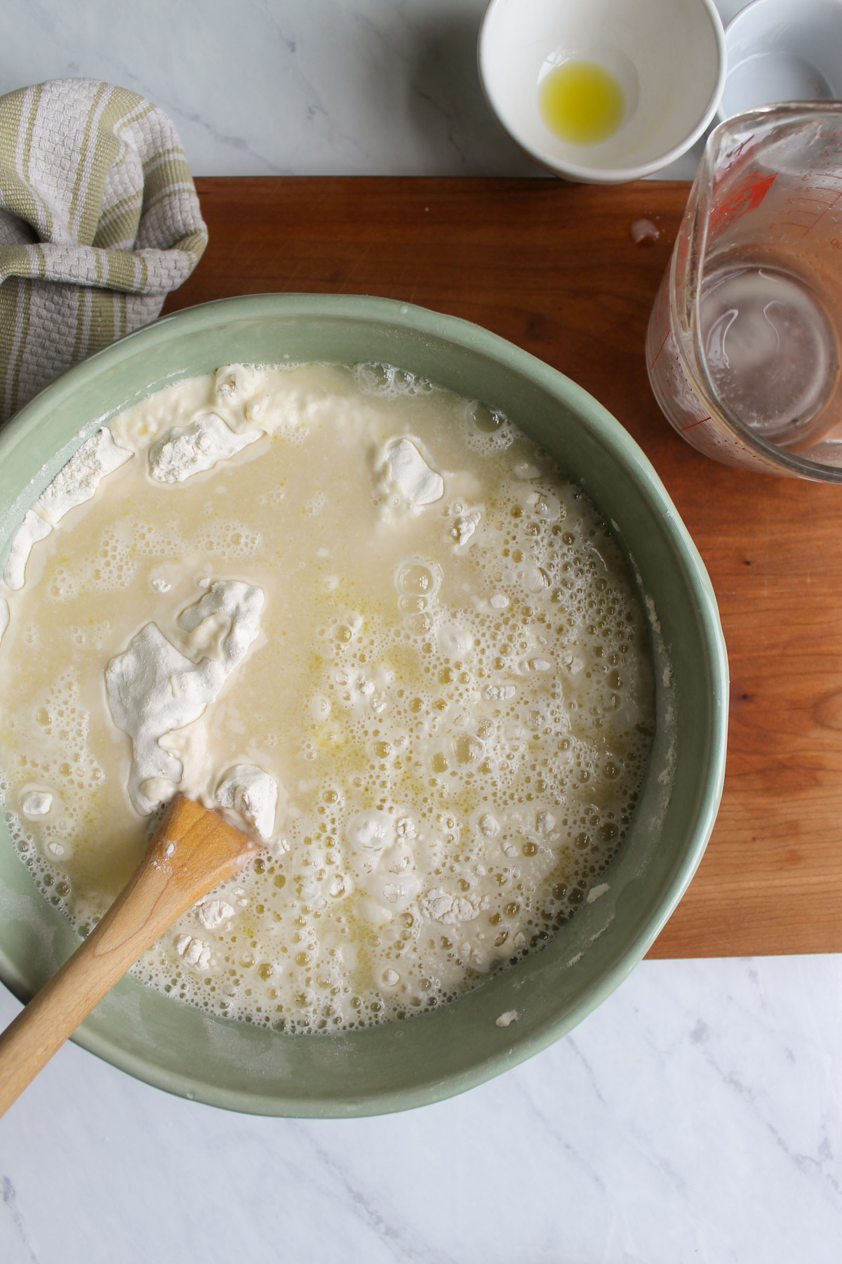 Liquid poured into a bowl of flour with a wooden spoon.