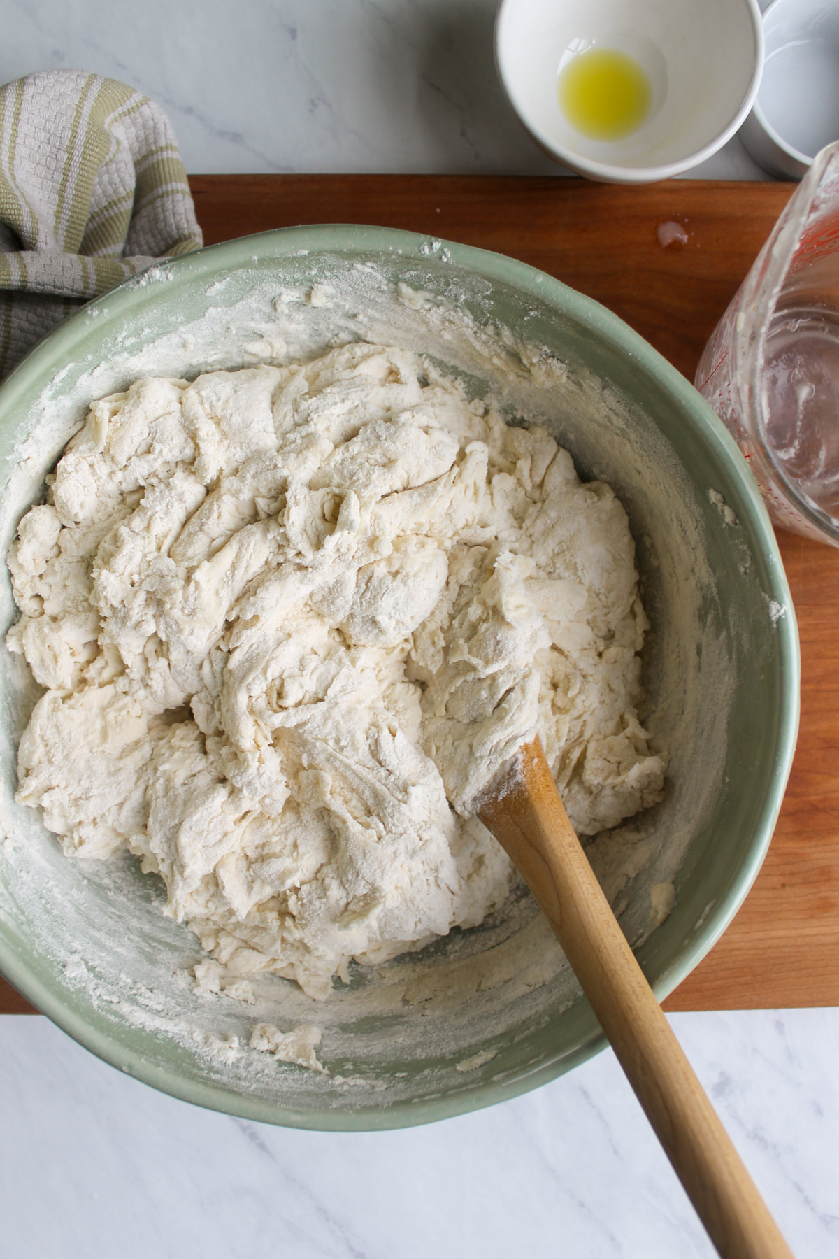 A bowl of bread dough mixed with a wooden spoon.