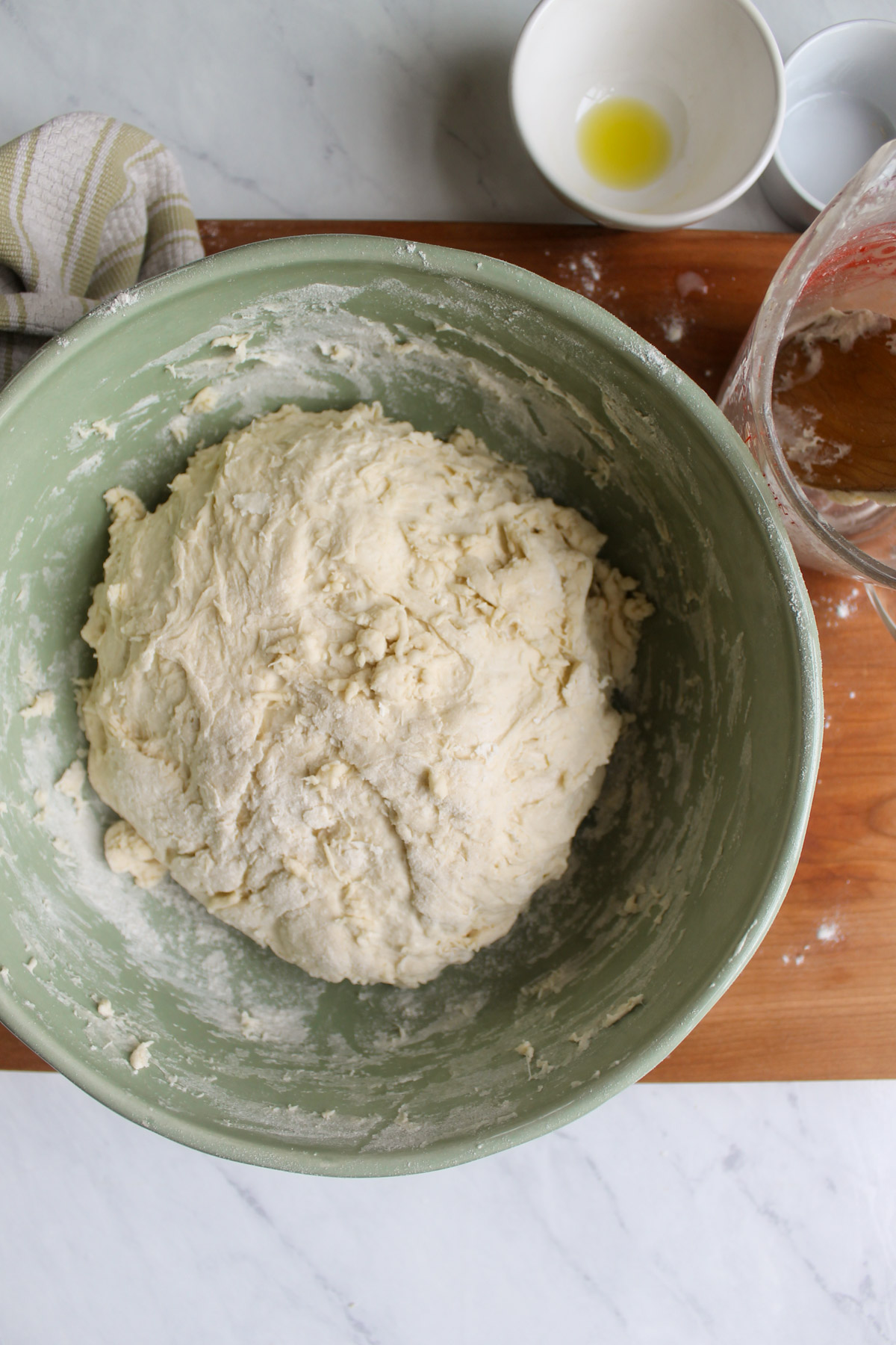 A ball of bread dough in a green bowl ready to rise overnight.