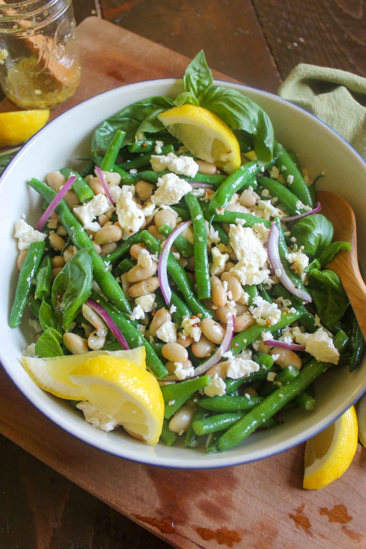 A bowl of green bean and white bean salad with lemons.