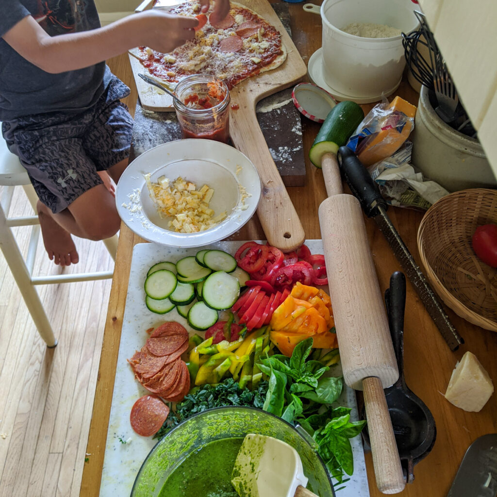 Vegetables and ingredients for pizza on a counter.