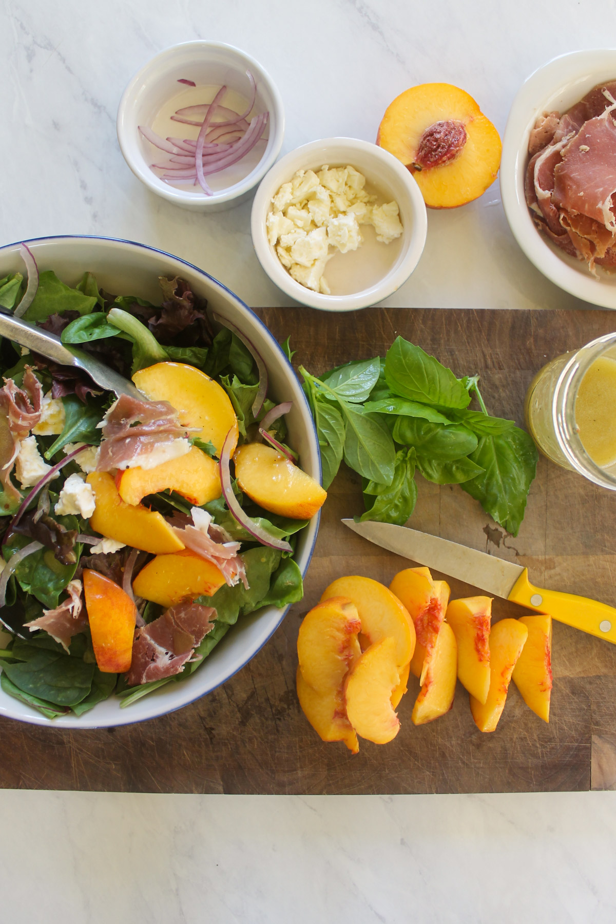 Sliced peaches next to a bowl of salad.