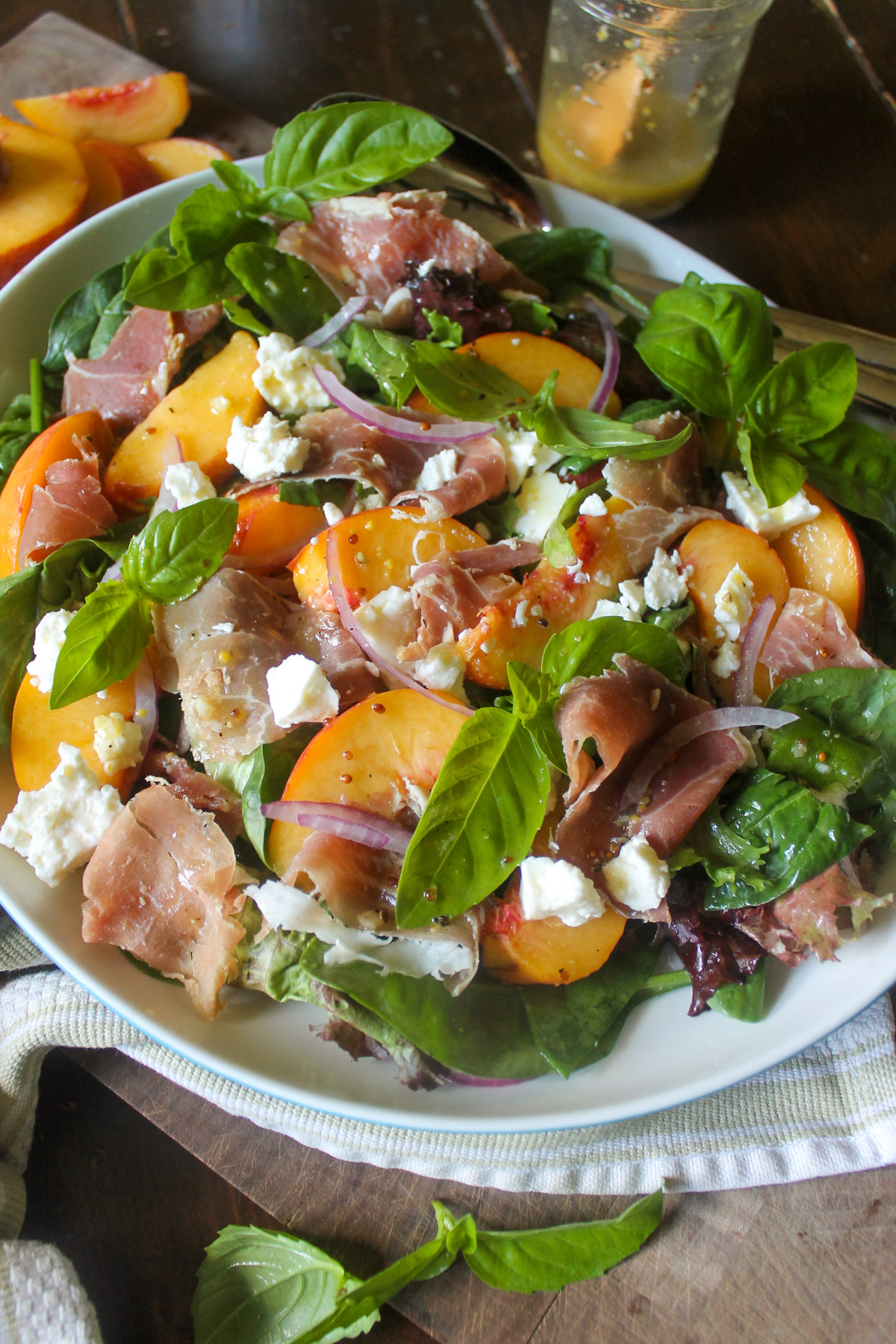 Peach prosciutto salad with basil leaves and feta cheese.