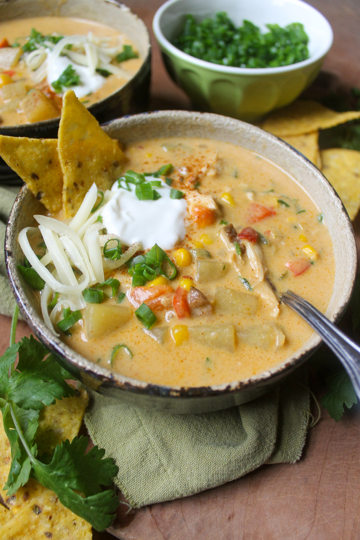 A bowl of spicy Chipotle Chicken Corn Chowder with chips, cheese and a dollop of yogurt.