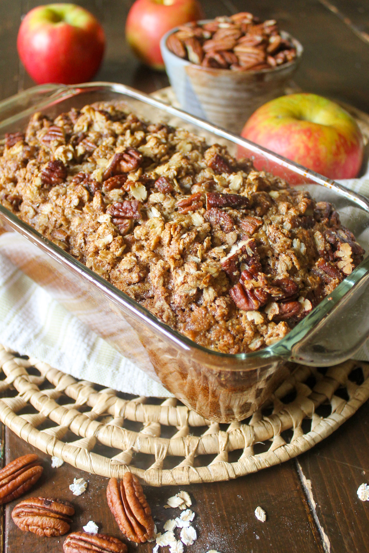 A loaf of apple bread in a glass pan with pecan oat topping.