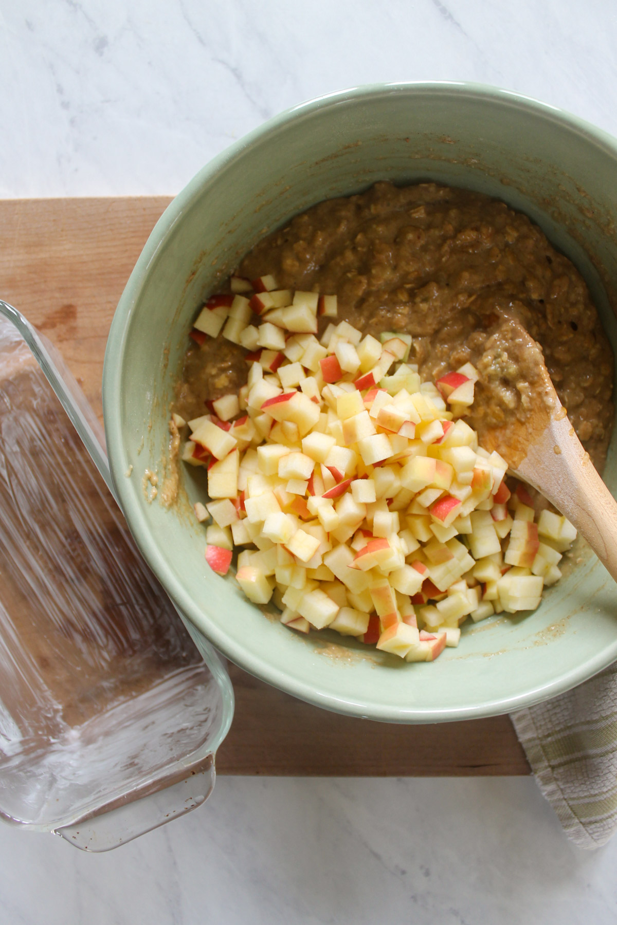 Adding chopped apples to a bowl of batter.
