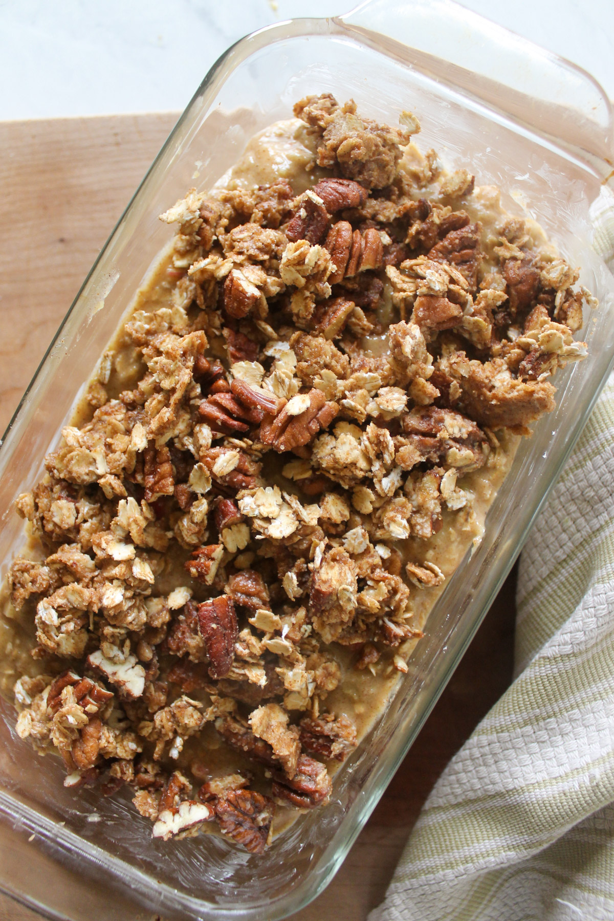 Apple bread batter with pecan oat topping in a loaf pan ready to bake.