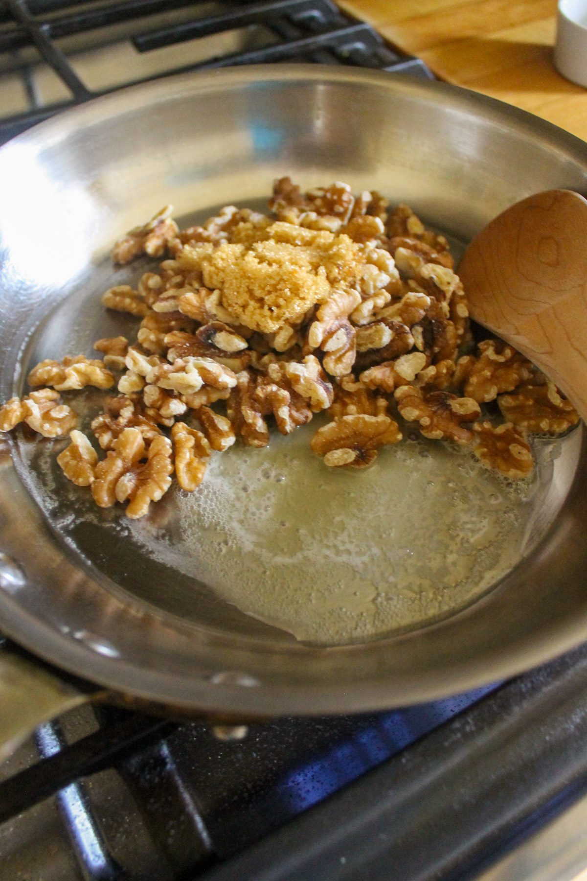 Making candied walnuts in a skillet with butter and brown sugar.
