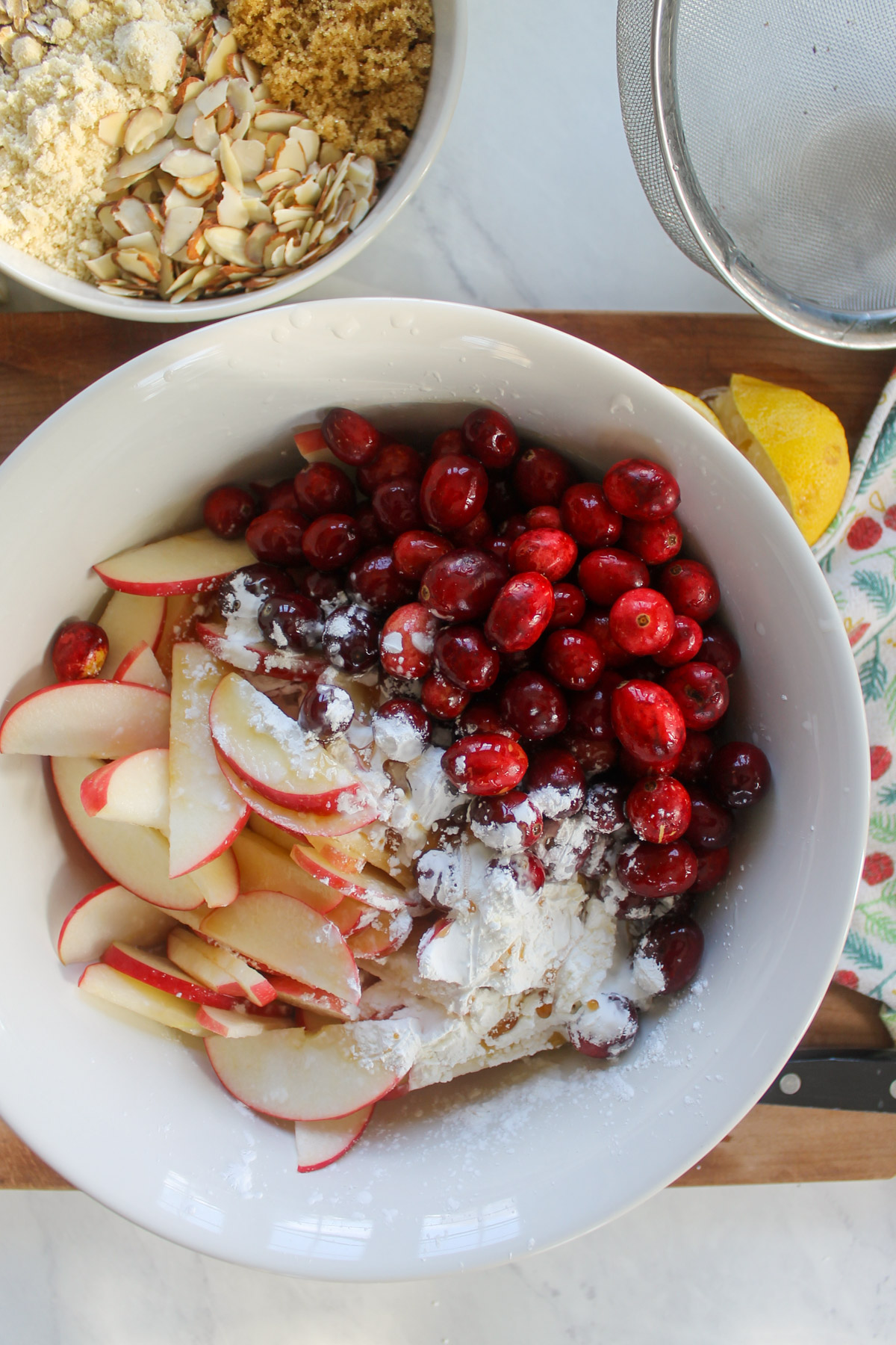 A bowl of sliced apples with fresh cranberries to be mixed for filling.