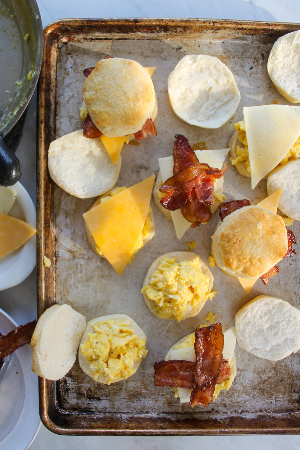 Assembling biscuit breakfast sandwiches with eggs, bacon and cheese.