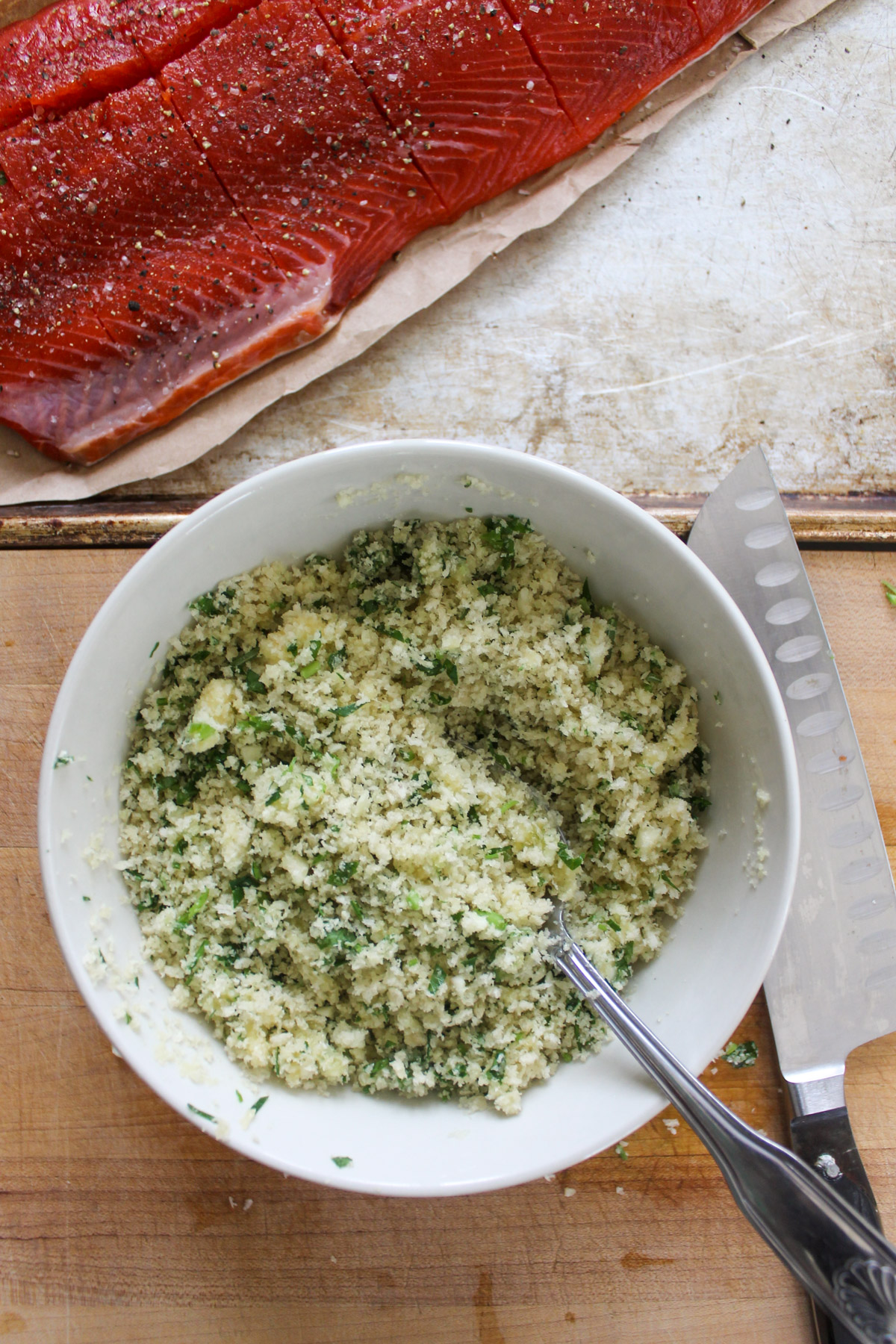 A bowl of panko bread crumbs mixed with garlic, herbs and melted butter.