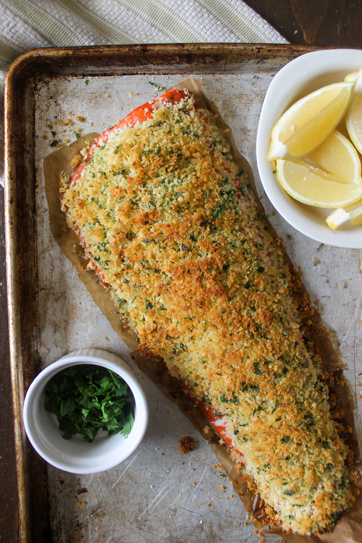 A baked salmon filet on a sheet pan with panko bread crumb topping.