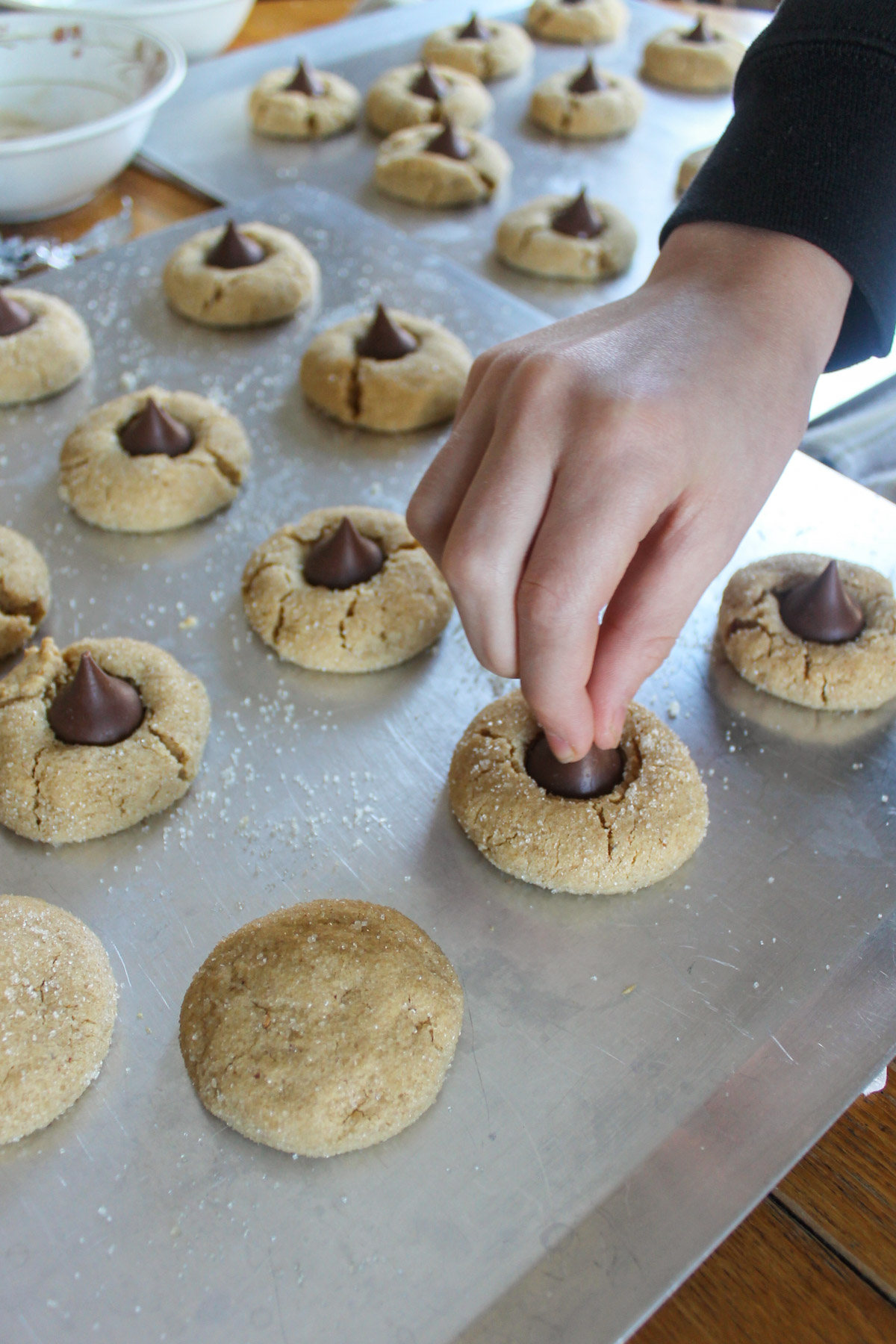 Pressing Hershey's kisses into baked peanut butter cookies.