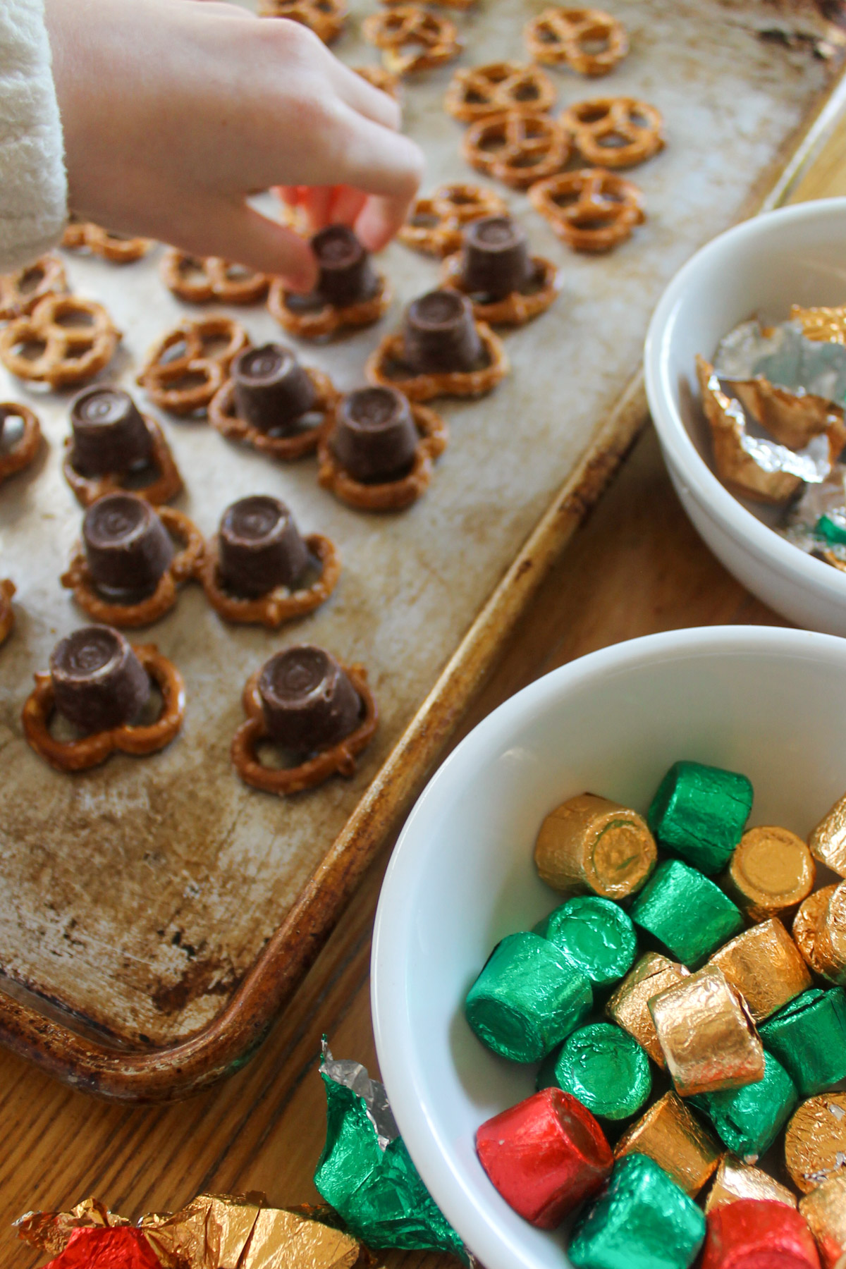Putting Rolo chocolate candies on pretzels on a sheet pan.