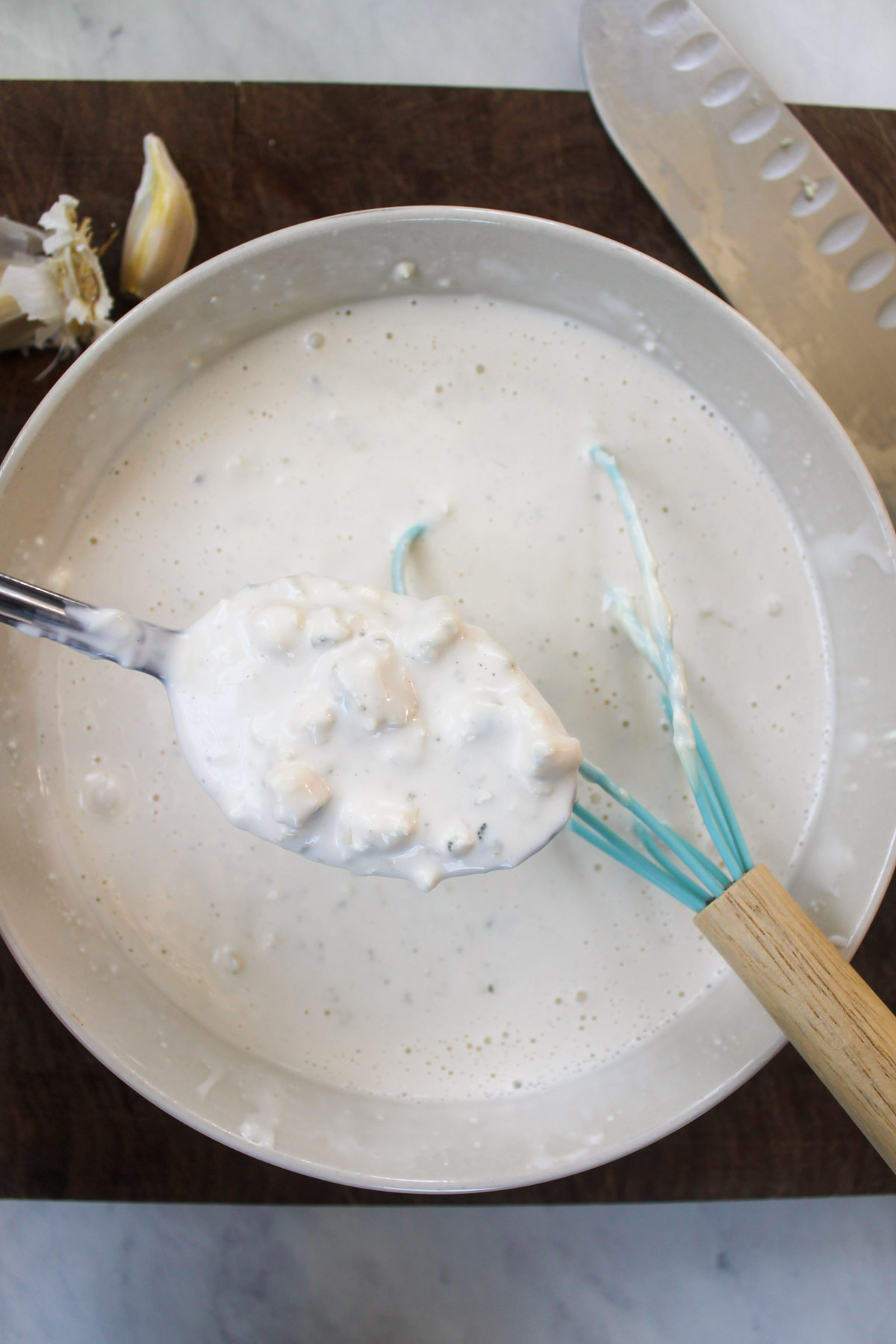 A spoonful of homemade blue cheese dressing over a bowl.