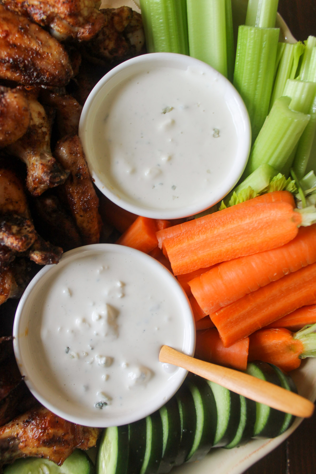 Cups of blue cheese dressing for dipping chicken wings and raw vegetables.