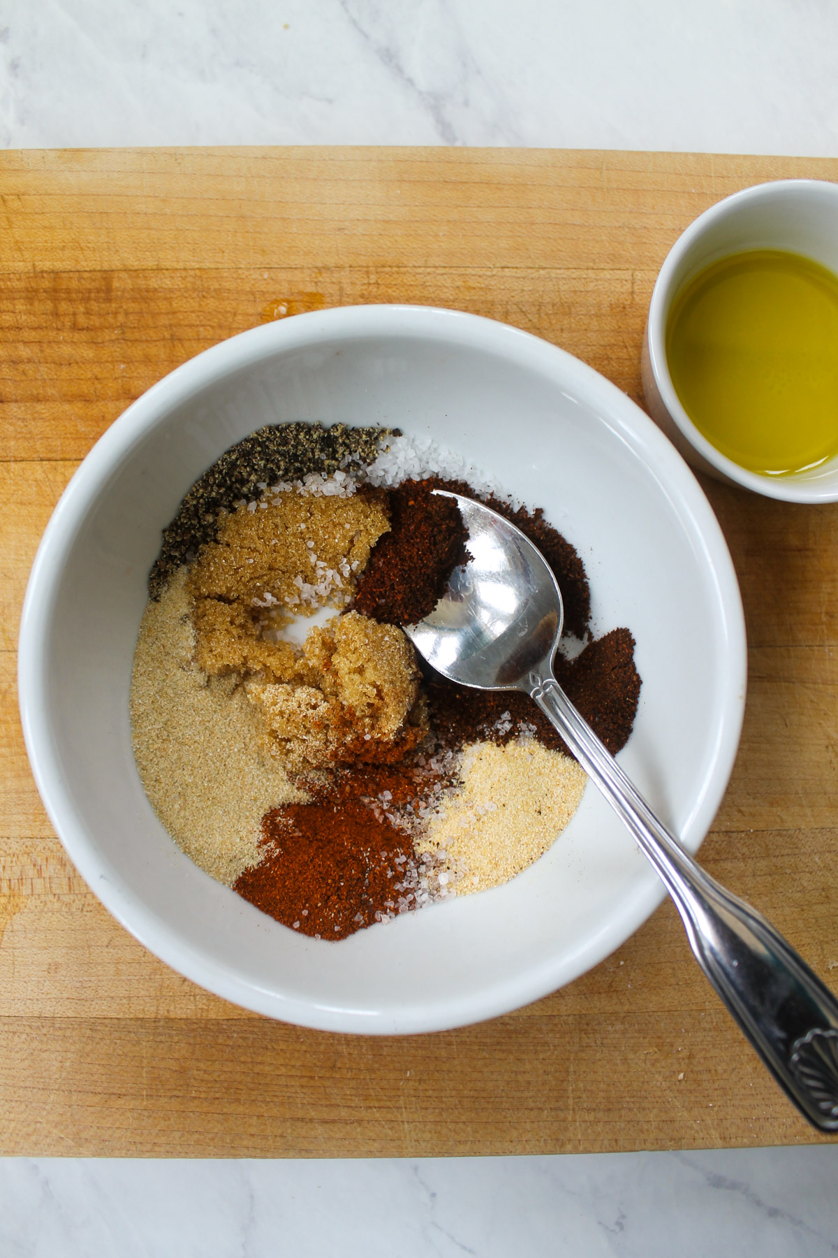 A white bowl of dry rub spices and seasonings.