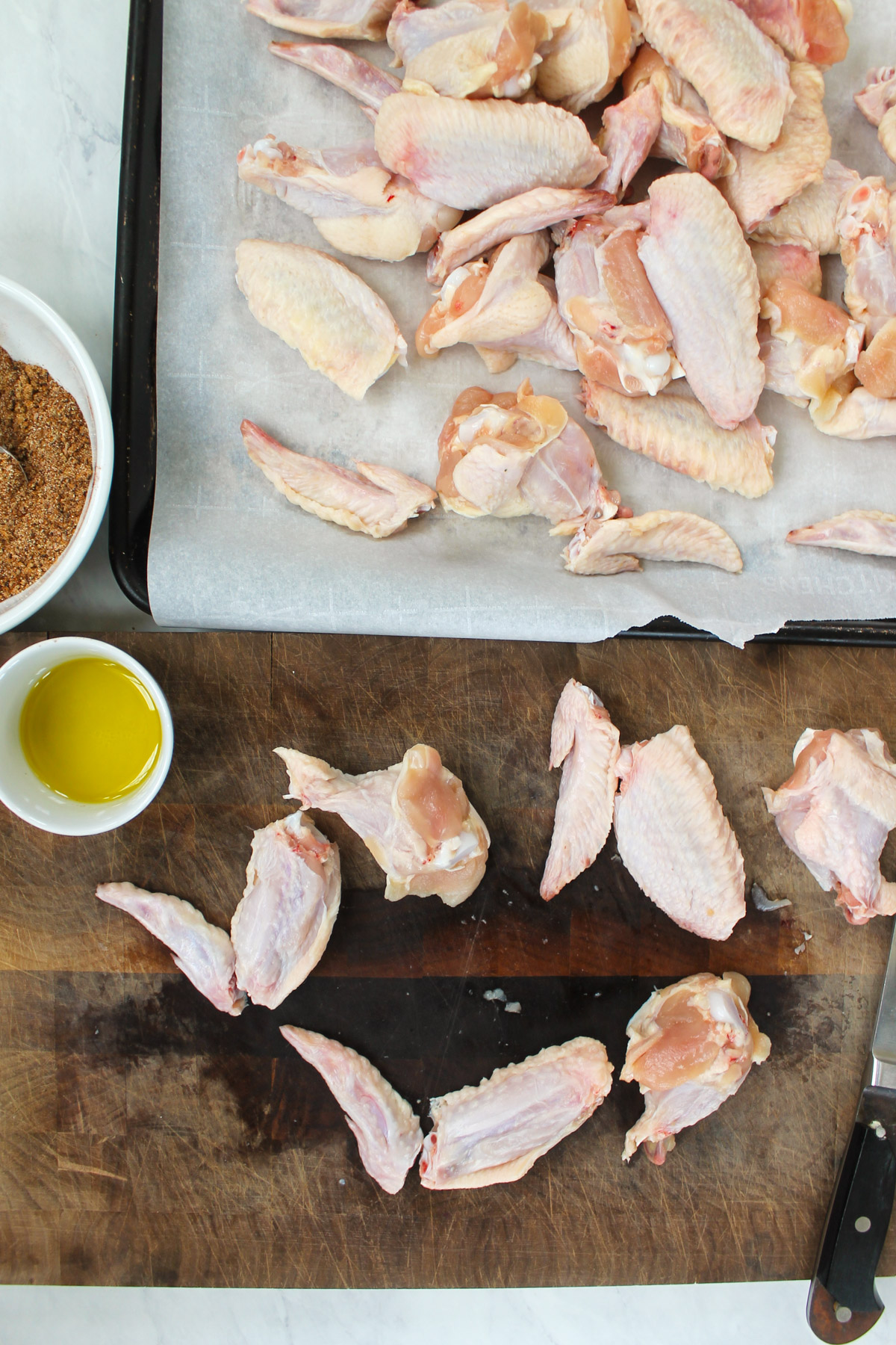 Cutting chicken wings into 3 parts on a cutting board.