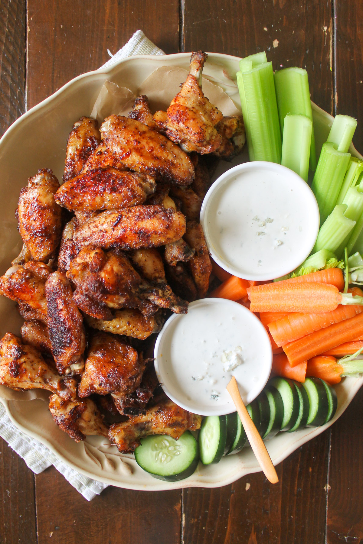 A platter of dry rub chicken wings with carrots, celery, cucumber and blue cheese dipping sauce.