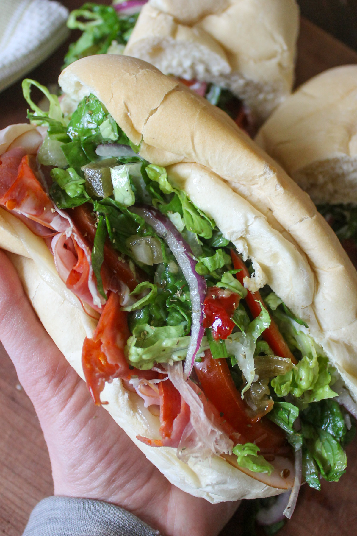 A grinder sandwich on a hoagie bun with vinegar dressed lettuce and peppers.