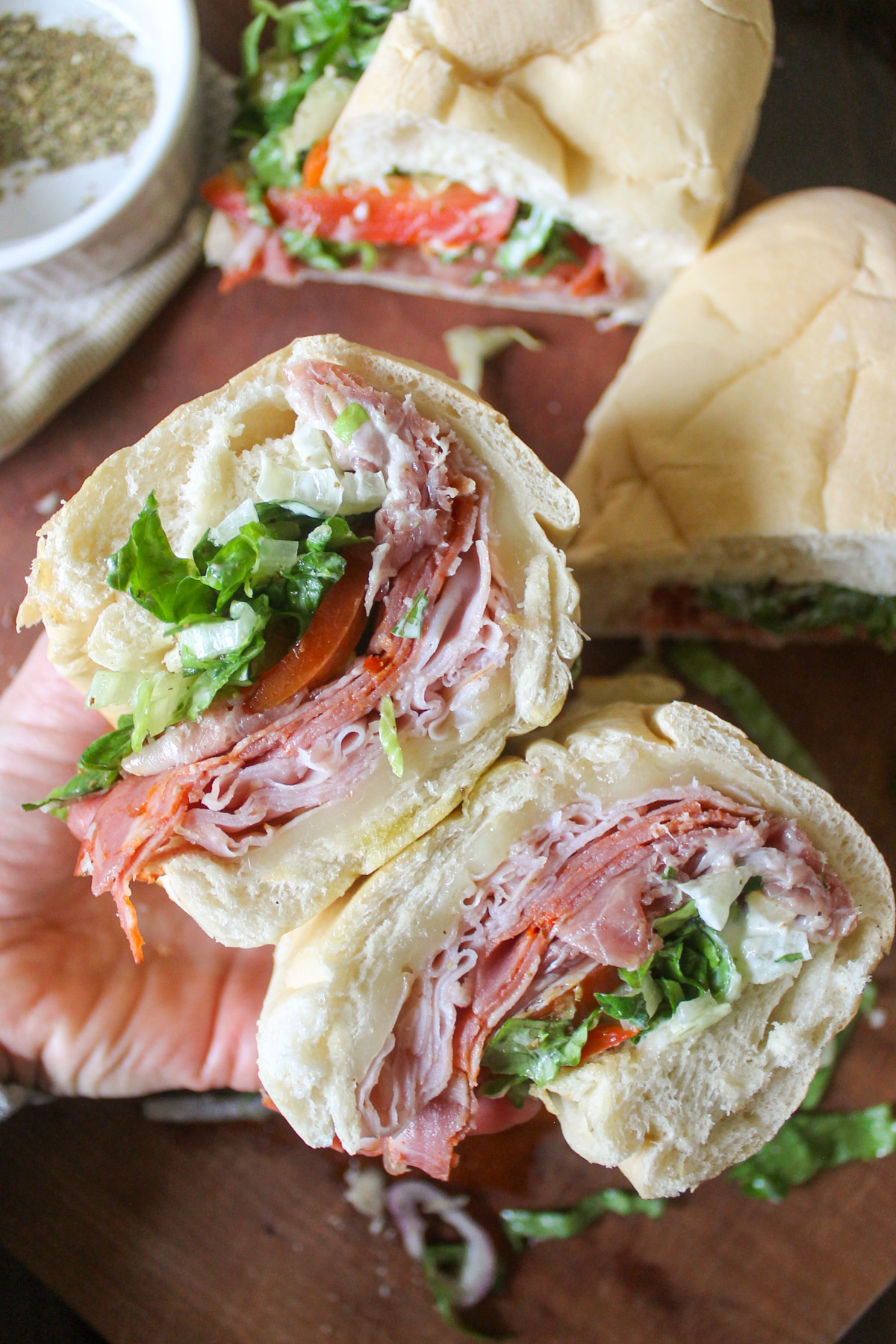 A sliced open Italian grinder sandwich with deli meats, cheese, tomato and lettuce.