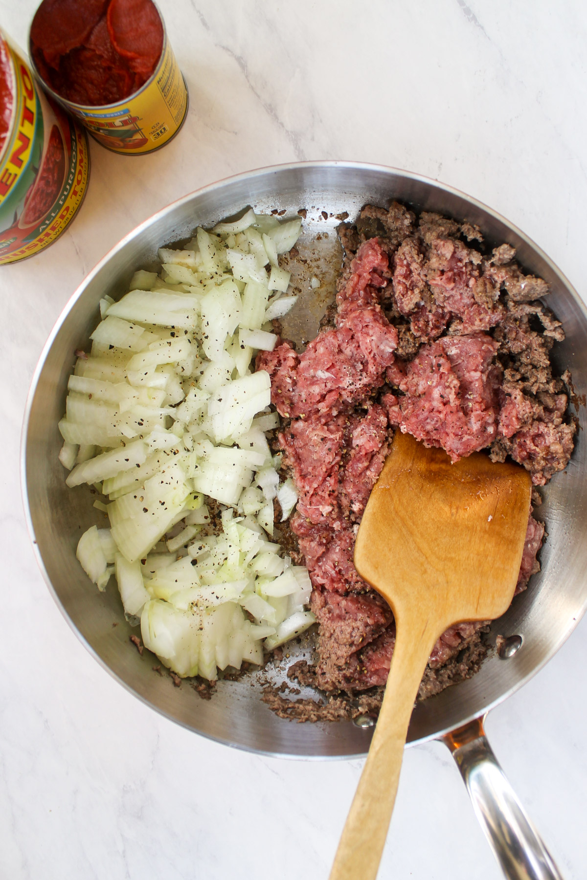 Browning raw ground beef with onions in a skillet.