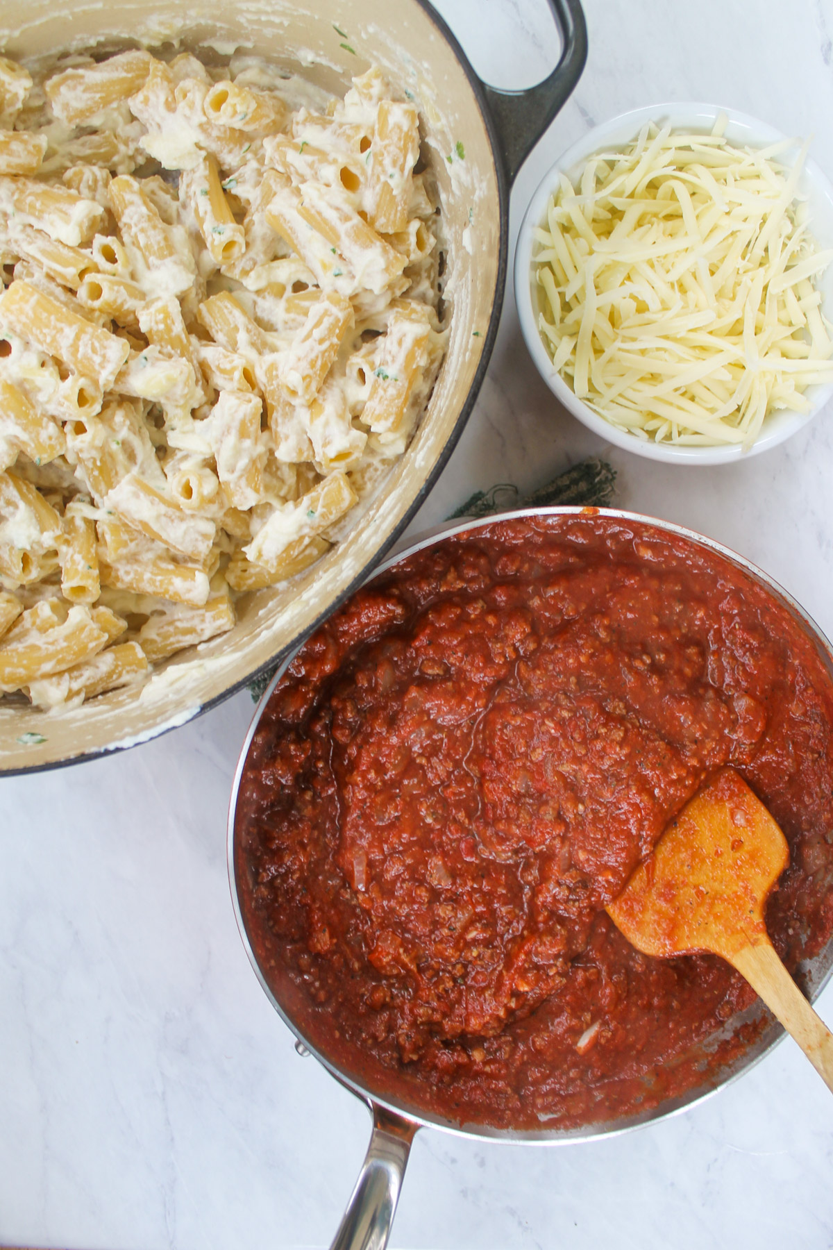 A skillet of tomato meat sauce and a pot of cheesy ricotta rigatoni. pasta.