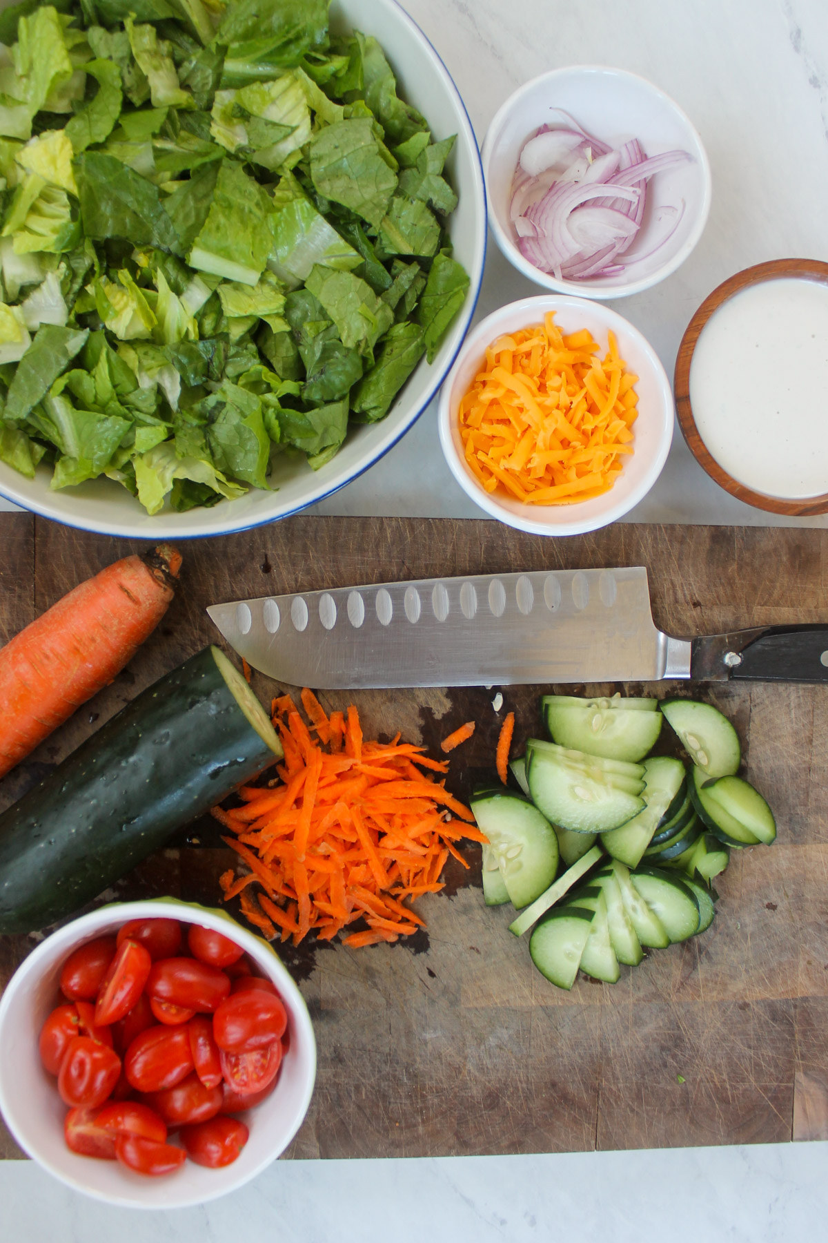 Salad vegetables prepped and chopped on a cutting board.