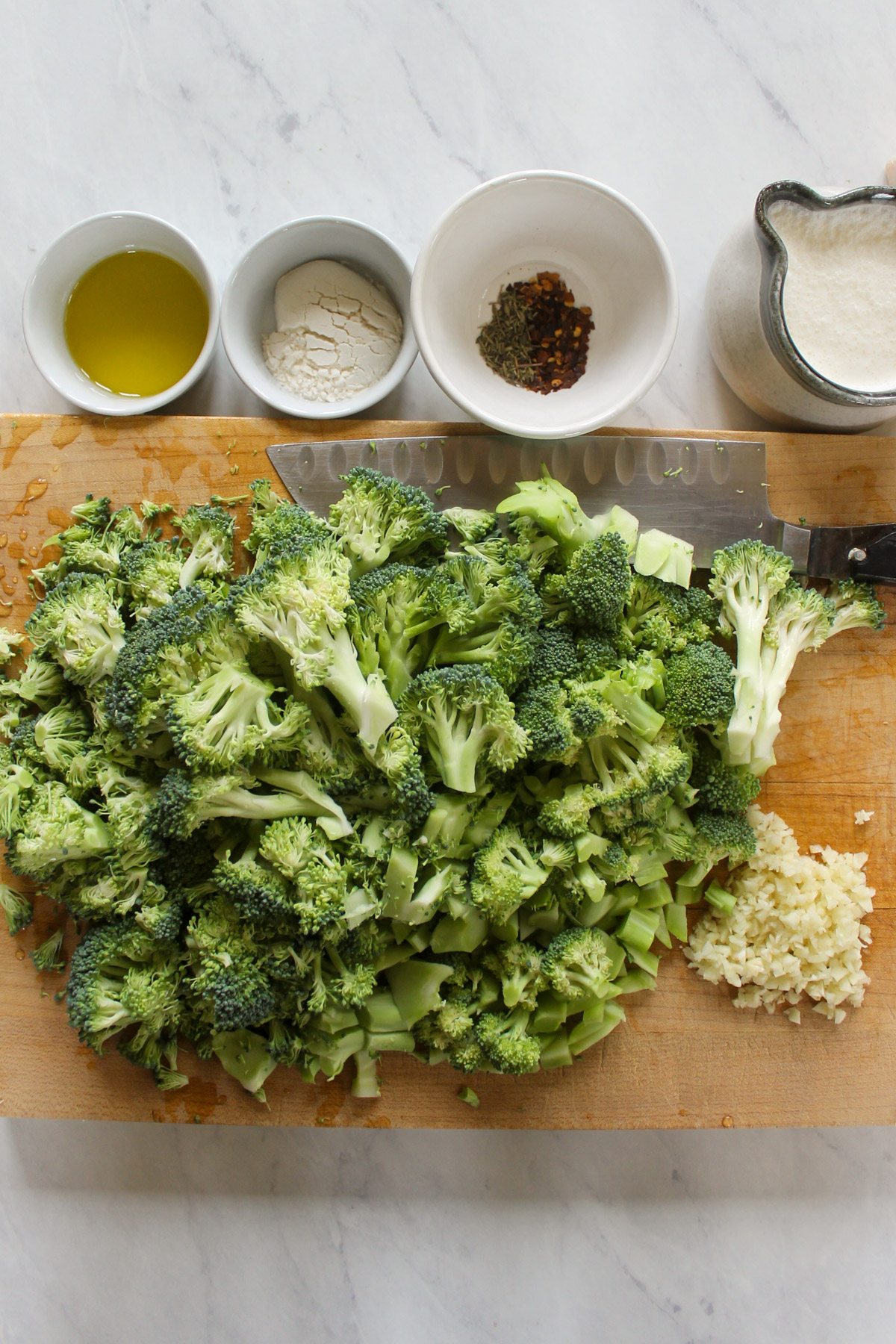 Chopped broccoli and garlic on a cutting board.