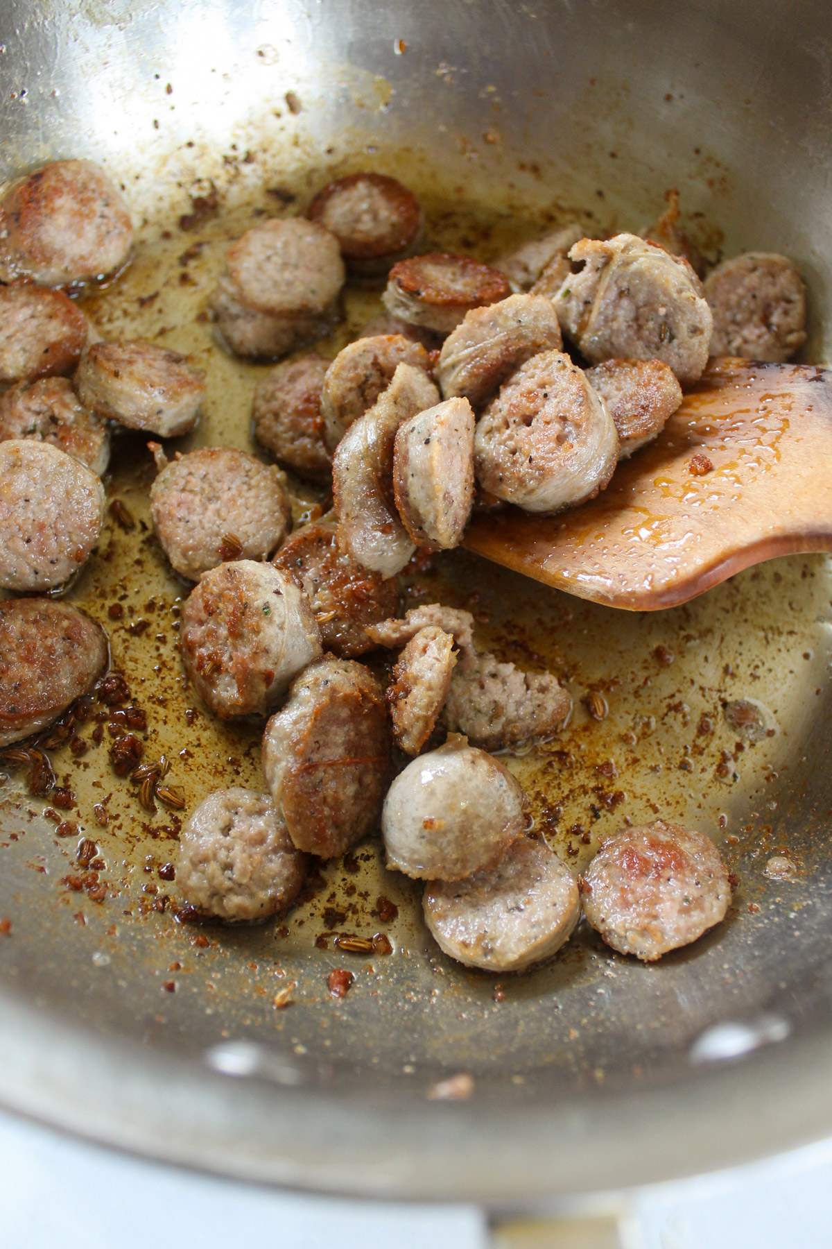 Browning sliced sausage links in a skillet.