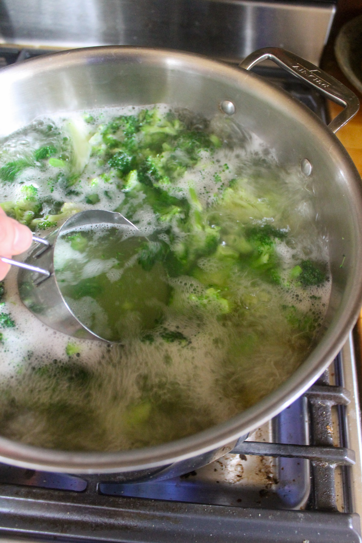Reserving pasta water from boiling rigatoni with broccoli.