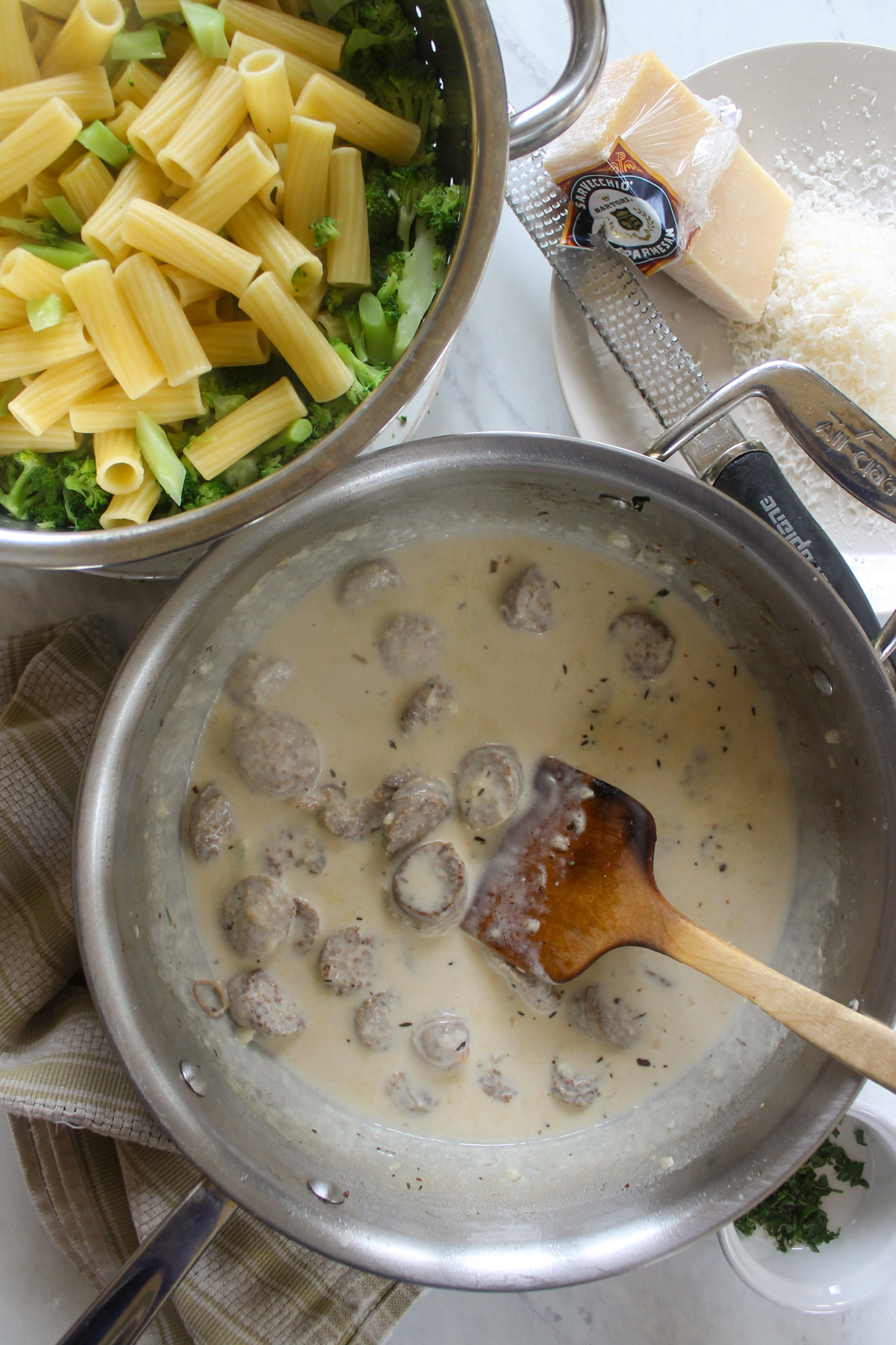 A skillet of cream sauce with sausage ready to add the pasta and broccoli.