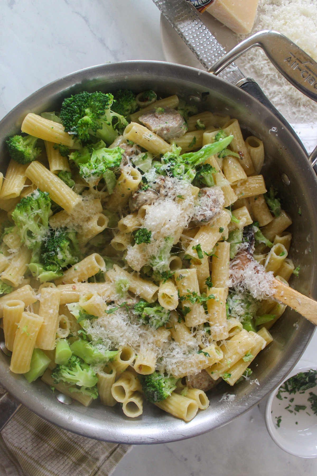 A big skillet of sausage and broccoli with pasta in a cream sauce.