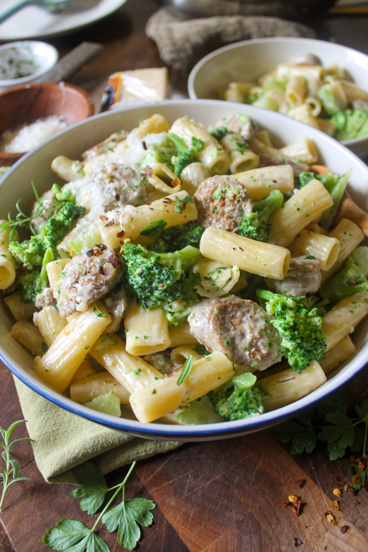 A serving bowl of rigatoni pasta with Italian sausage and broccoli.