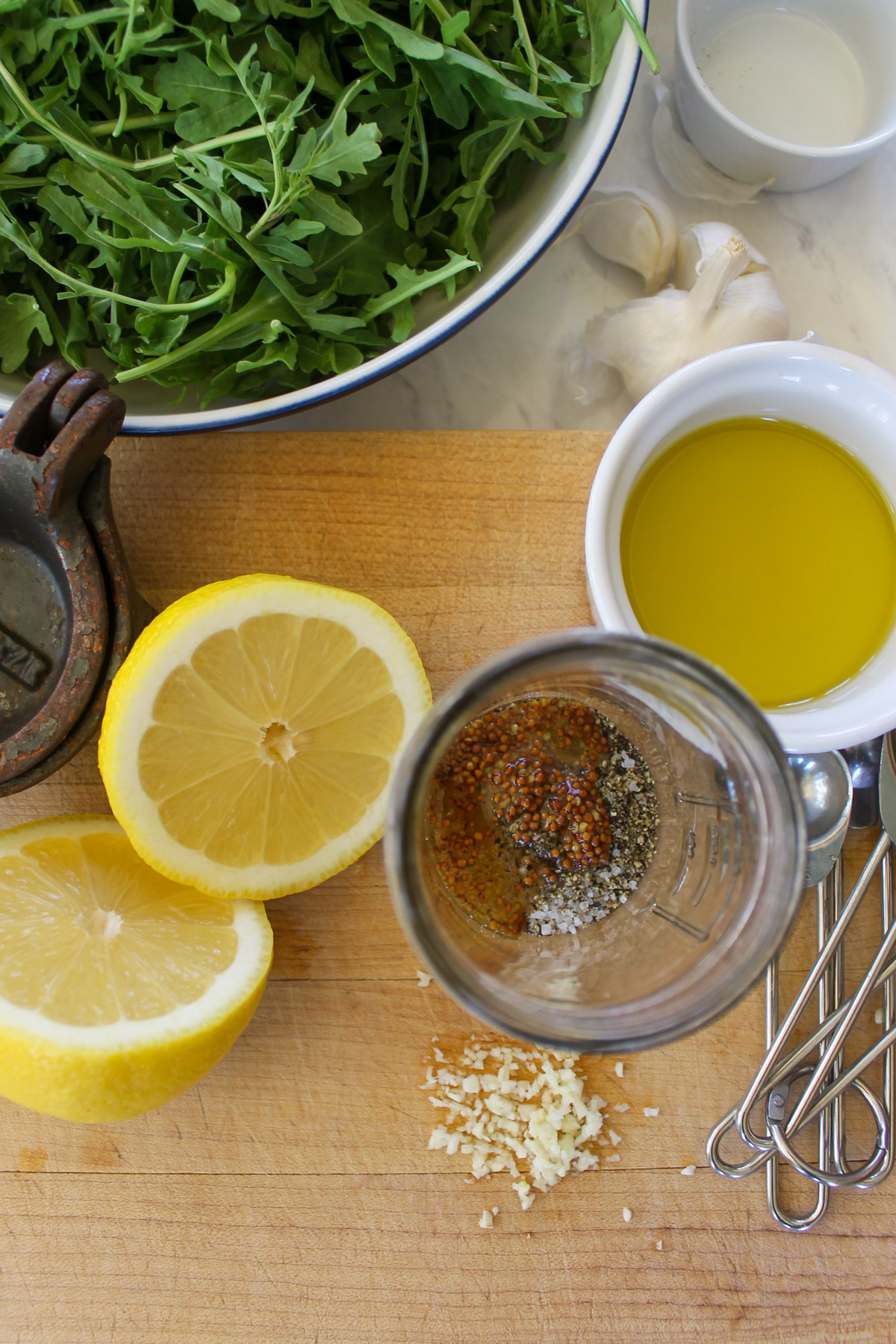 Making lemon vinaigrette in a jar with minced garlic, dijon and honey.