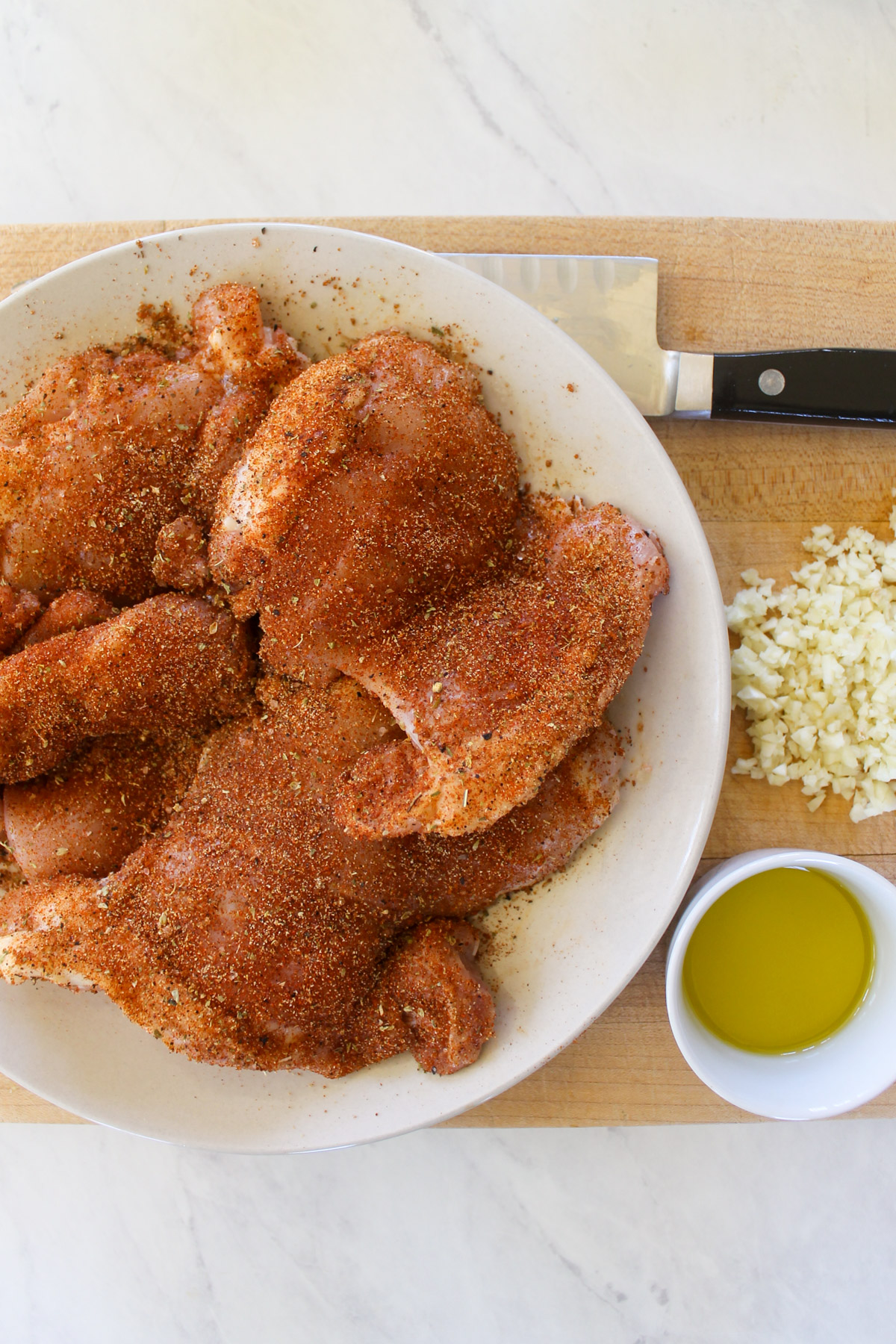 Raw chicken with blackening seasoning on a plate.