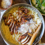 A skillet of Alfredo pasta linguine with sliced blackened chicken.