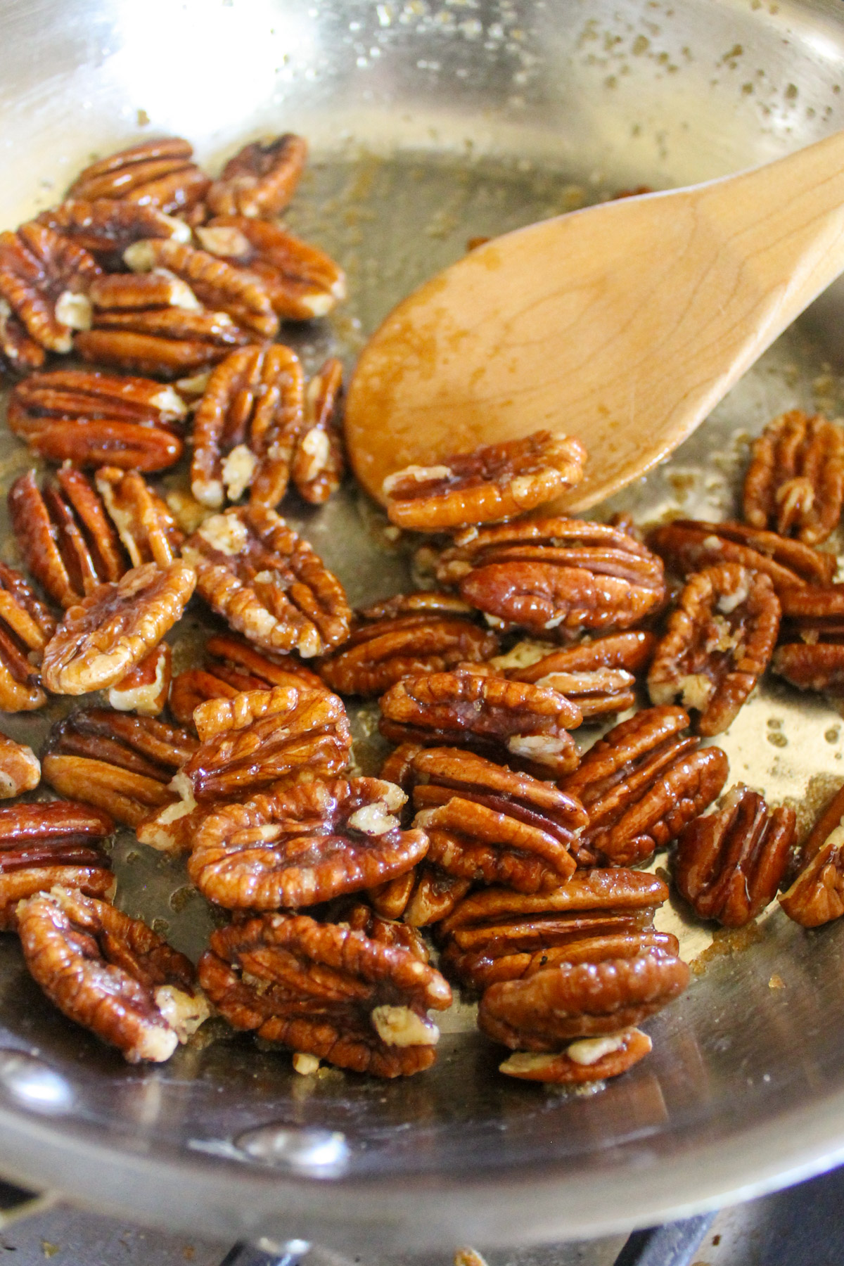 Candied pecans in a skillet with butter and brown sugar.